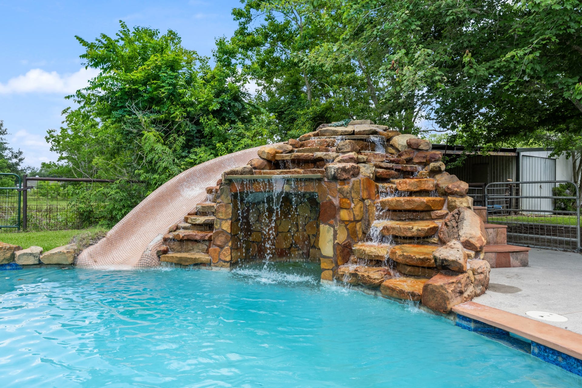 15602 Fir Road, Santa Fe, TX 77517 Resort-style pool feature with a custom rock waterfall, cascading water elements, and an impressive built-in slide that creates a true private retreat. Perfect for outdoor entertaining and summer fun.