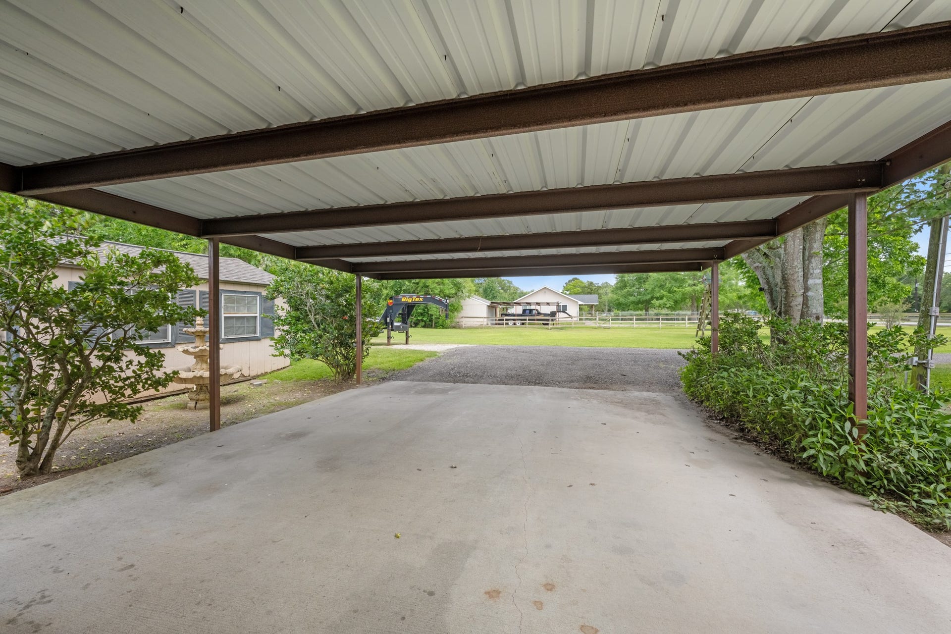 15602 Fir Road, Santa Fe, TX 77517 Covered parking area with ample space for two vehicles, trailers, or recreational equipment. The surrounding open yard and mature landscaping add to the propertys versatility and country-style appeal.