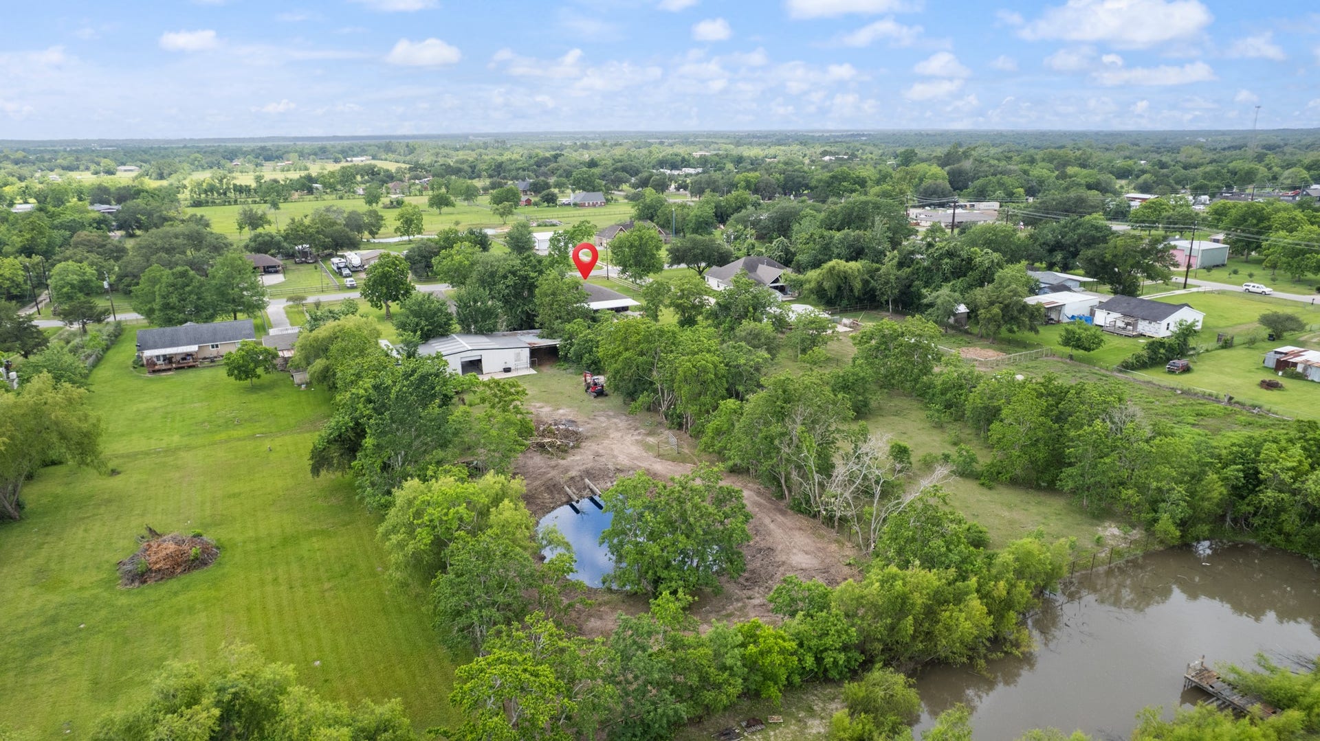 15602 Fir Road, Santa Fe, TX 77517 Sweeping aerial perspective highlighting the propertys expansive grounds, mature trees, open pasture areas, and additional land features. Ideal for those seeking extra space, privacy, and room for livestock, recreation, or future projects.