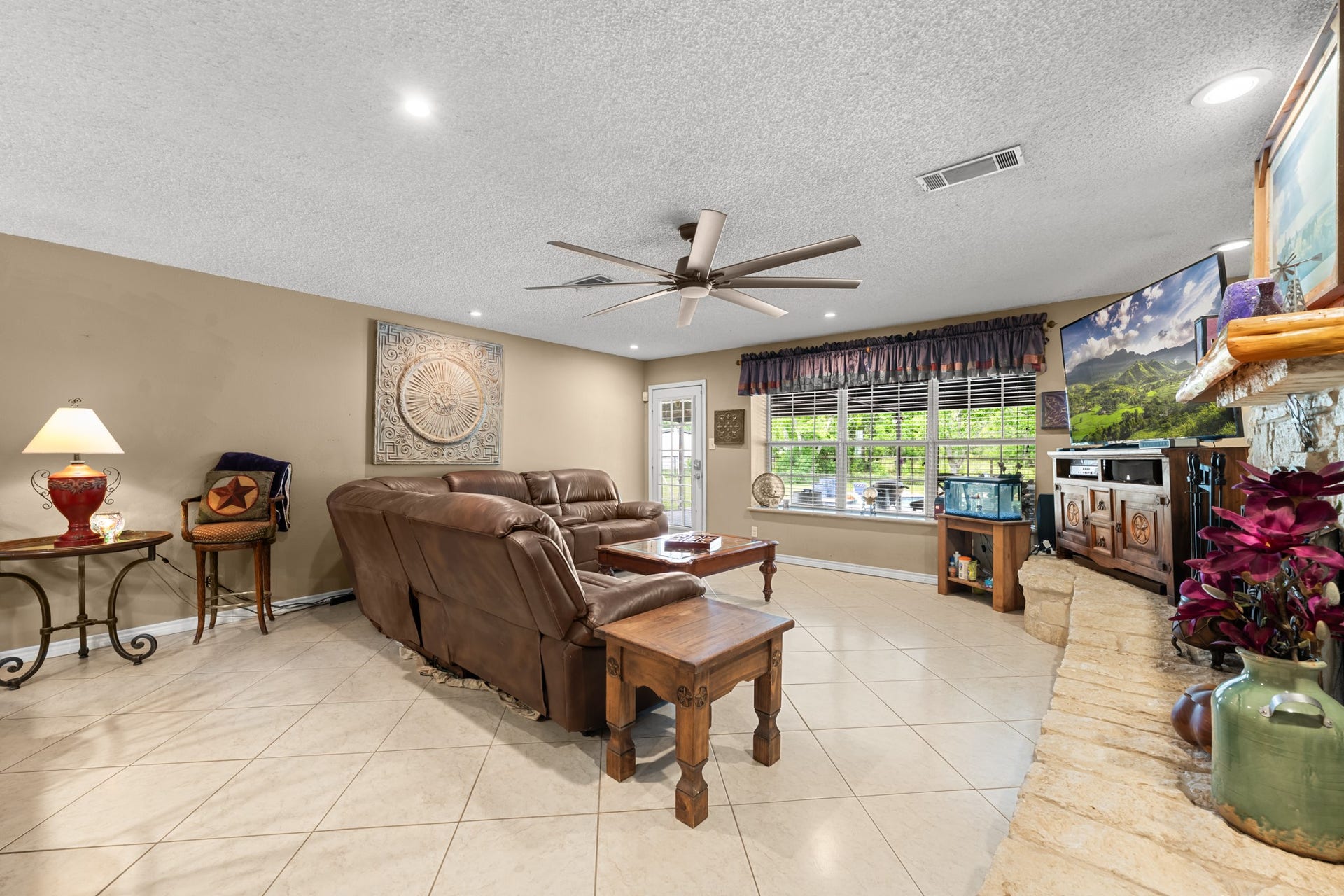 15602 Fir Road, Santa Fe, TX 77517 Spacious open living room featuring a beautiful stone fireplace, recessed lighting, and oversized windows overlooking the property. The expansive layout and neutral finishes provide the perfect setting for everyday living and entertaining alike.