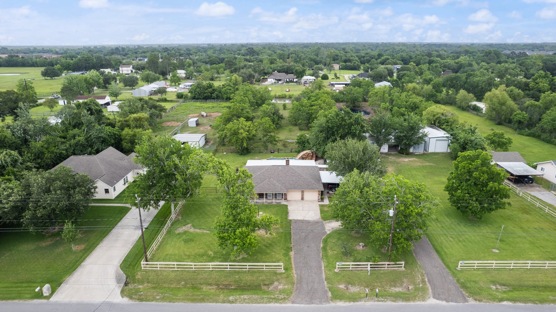 15602 Fir Road, Santa Fe, TX 77517 Expansive aerial view showcasing the home, pool area, horse barn, insulated workshop, and sprawling acreage surrounded by mature trees. This unique property offers a blend of residential comfort, outdoor recreation, and functional space for hobbies or livestock.
