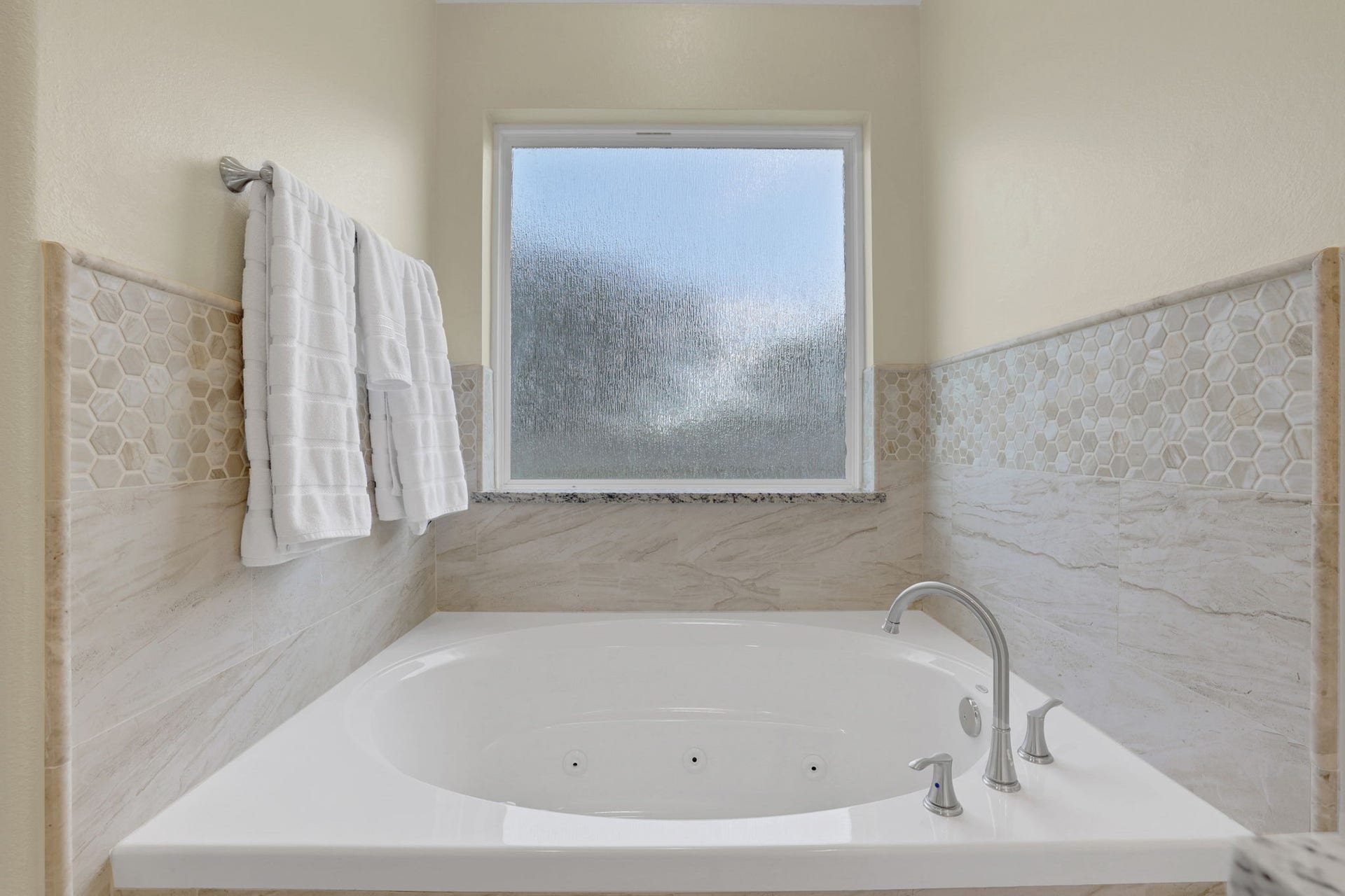 12751 County Road 283, Alvin, TX 77511 Luxurious bathroom featuring a spacious jetted tub, elegant tile accents, and a frosted window for privacy.