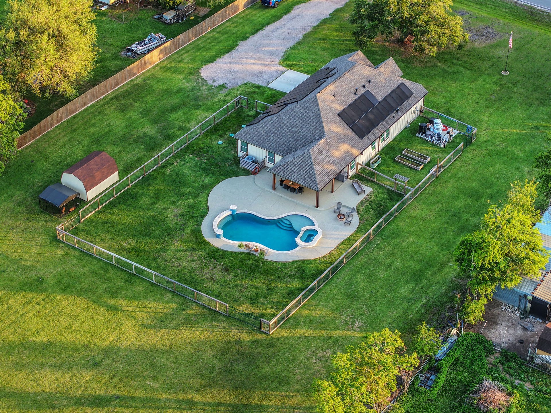 12751 County Road 283, Alvin, TX 77511 Expansive fenced property featuring a charming home complemented by a luxurious pool and a spacious patio, ideal for outdoor relaxation and entertaining.