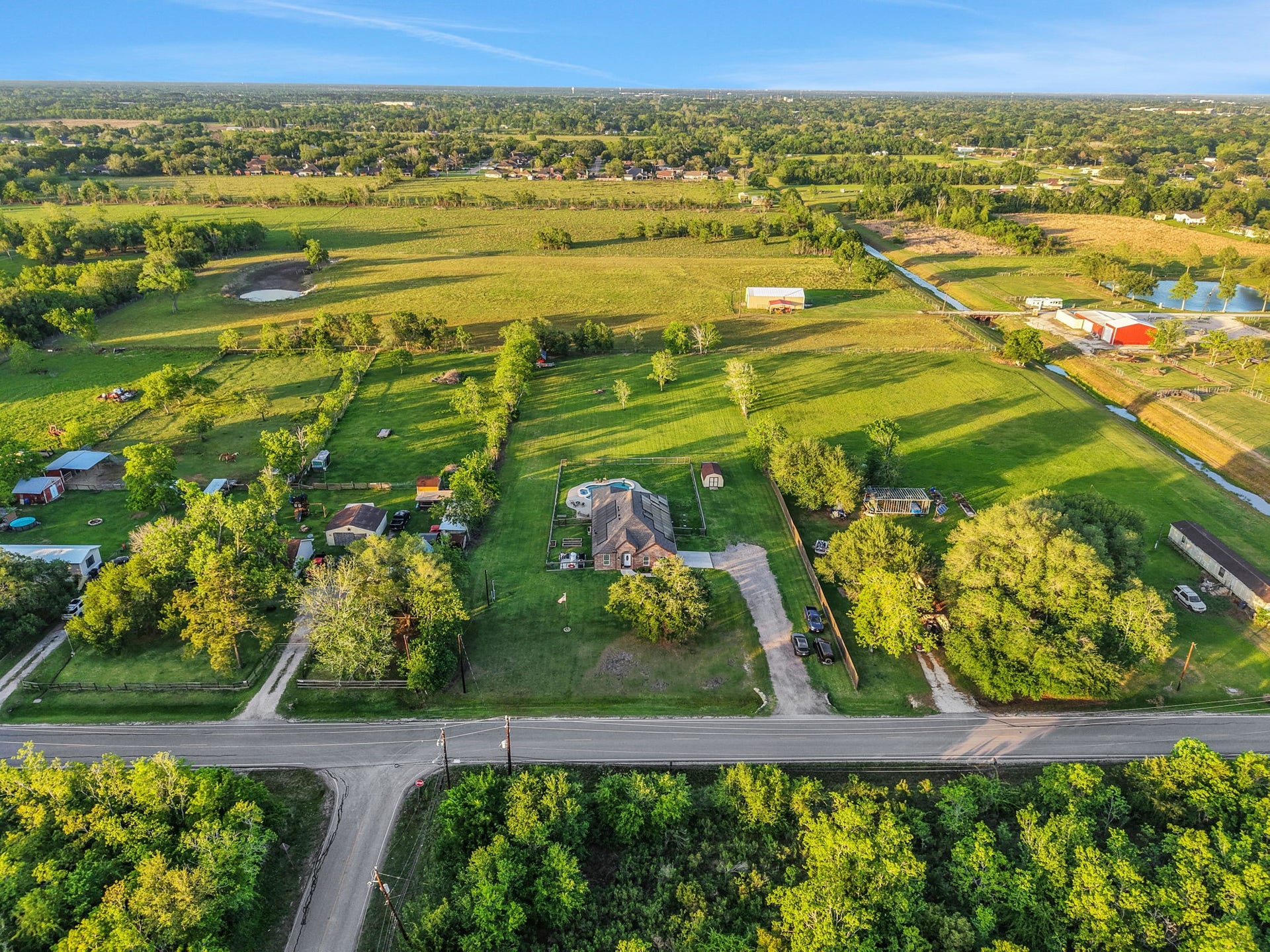 12751 County Road 283, Alvin, TX 77511 Expansive property with a charming home set amidst lush greenery and open fields, offering privacy and serene country living.