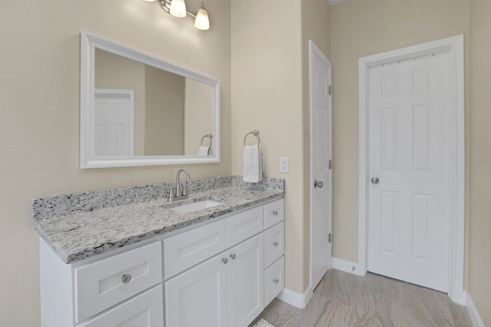 12751 County Road 283, Alvin, TX 77511 Elegant primary bathroom featuring a sleek granite countertop, modern white vanity, and ample storage, complemented by soft lighting and neutral walls.
