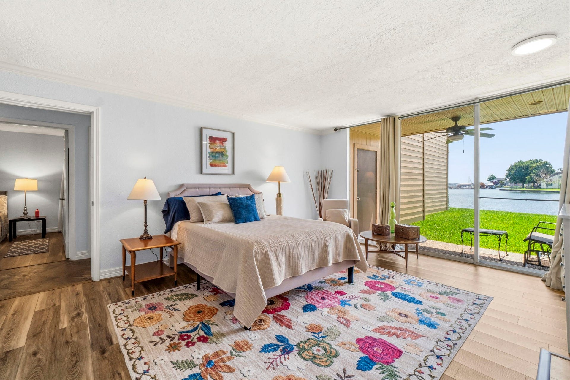 Waterfront Primary Retreat Spacious primary bedroom featuring a cozy fireplace, wall-mounted TV, and breathtaking lake views through expansive sliding glass doors.