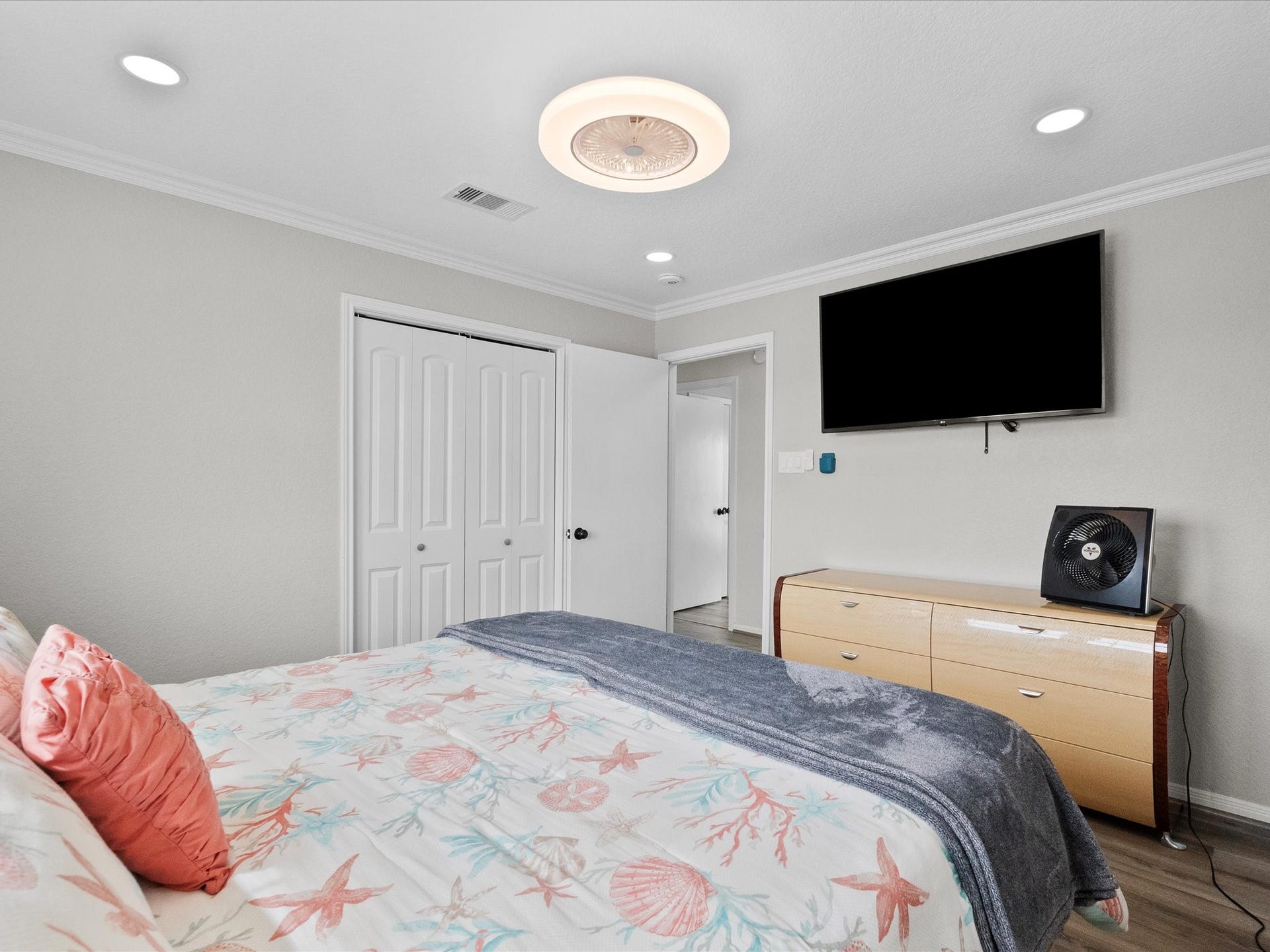 319 Francis Cove, Surfside Beach, TX 77541 This bedroom features soft neutral walls, recessed lighting, and a modern ceiling fixture. It includes a cozy bed with ocean-themed bedding, a wall-mounted TV, a sleek dresser, and a double-door closet. The room is bright and inviting, perfect for relaxation.