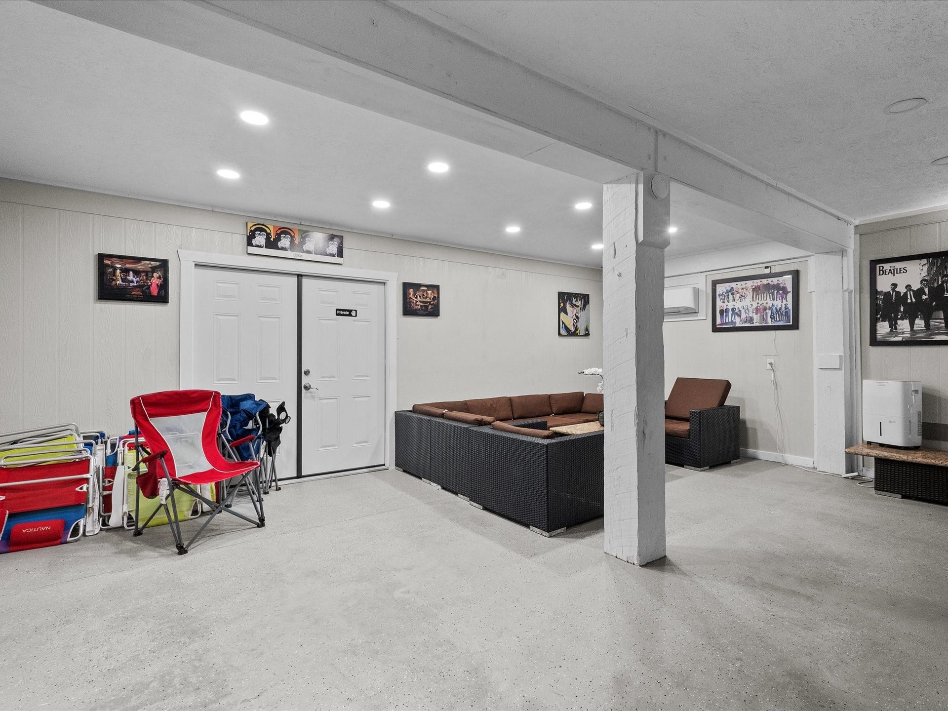 319 Francis Cove, Surfside Beach, TX 77541 This spacious basement rec room features ample seating, bright lighting, and wall-mounted decor, perfect for relaxation and entertainment.