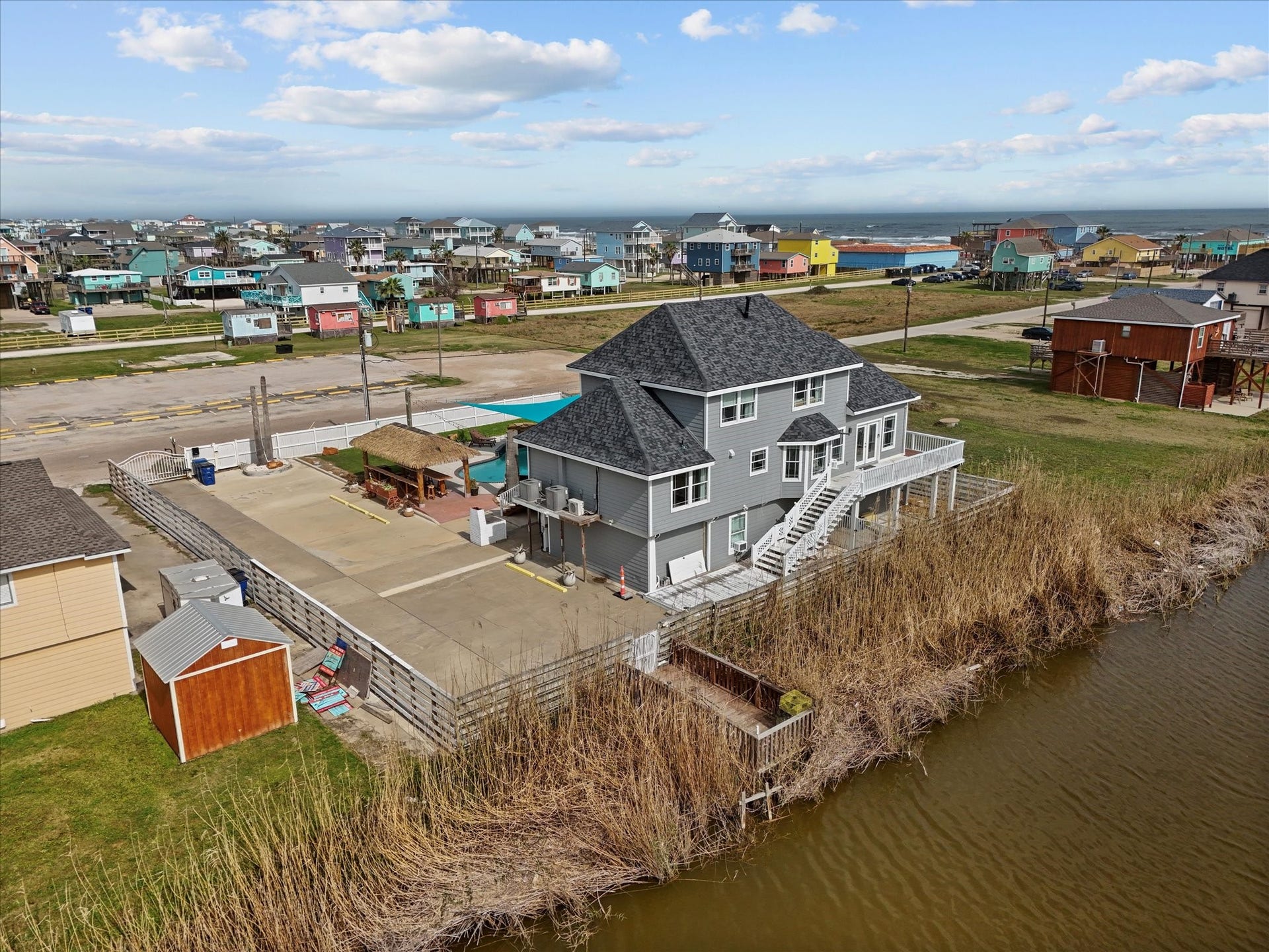 319 Francis Cove, Surfside Beach, TX 77541 This waterfront home features a spacious deck with scenic views, a well-maintained exterior, and a large driveway. It offers a peaceful setting with nearby access to other colorful homes and amenities.