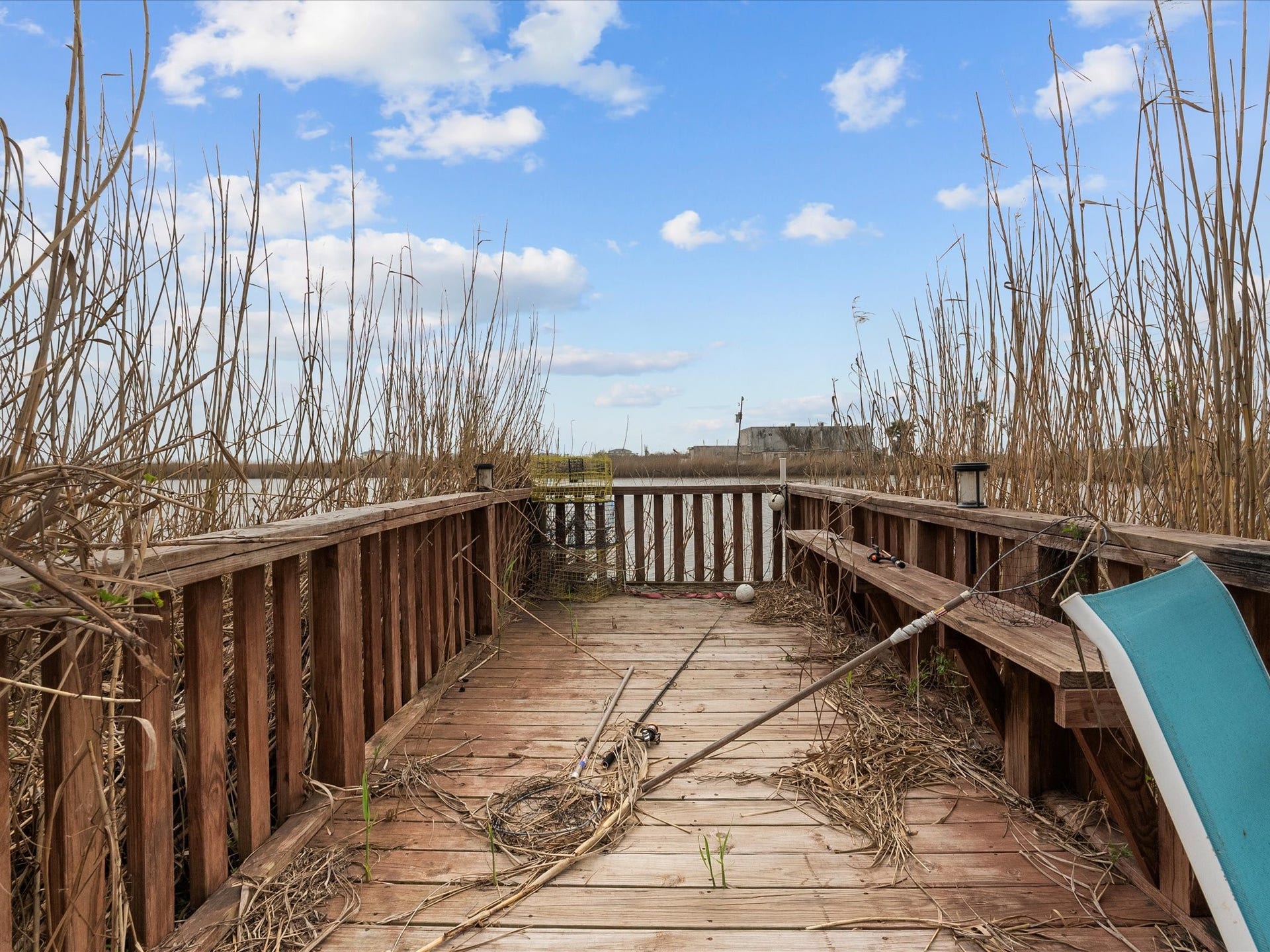 319 Francis Cove, Surfside Beach, TX 77541 Charming waterfront deck surrounded by tall reeds, offering a rustic, natural setting perfect for relaxation and enjoying serene views.
