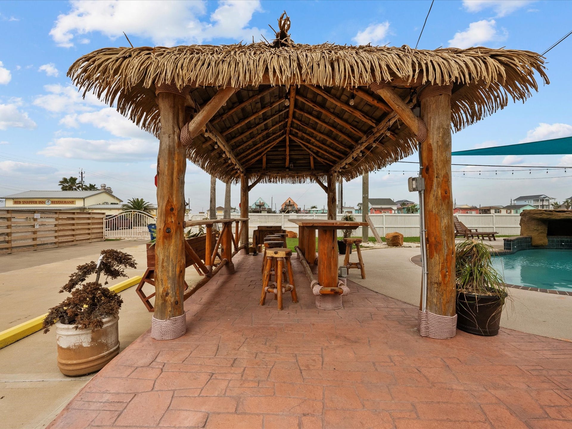 319 Francis Cove, Surfside Beach, TX 77541 This photo showcases a tropical-themed outdoor area featuring a rustic tiki hut with seating, adjacent to a pool. The space is ideal for entertaining and relaxation, offering a laid-back, resort-like atmosphere.
