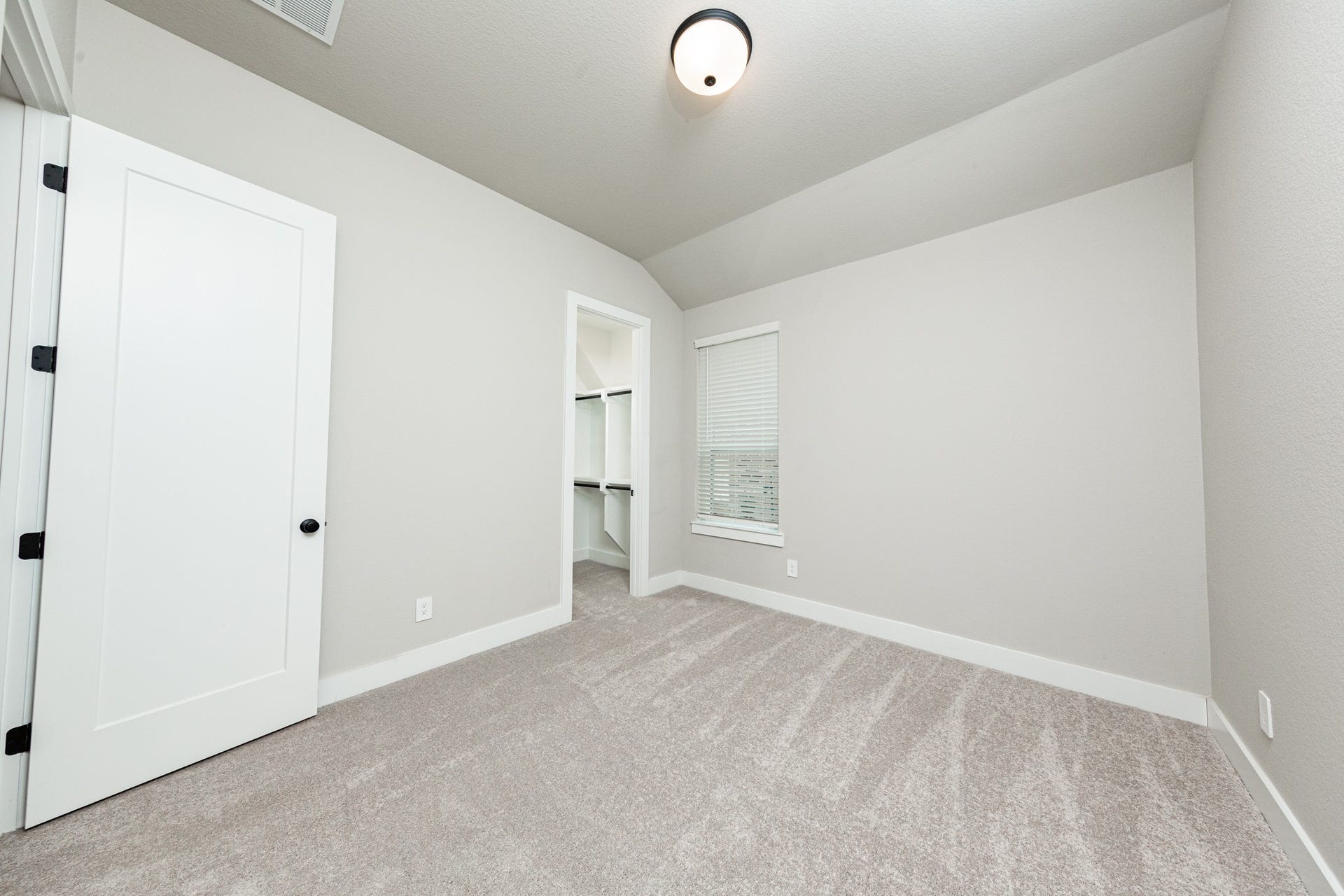 41418 Threadgill Way, Montgomery, TX 77316 This secondary bedroom features a sloped ceiling, plush carpet flooring, a large window, a walk-in closet, and an ensuite secondary bathroom.