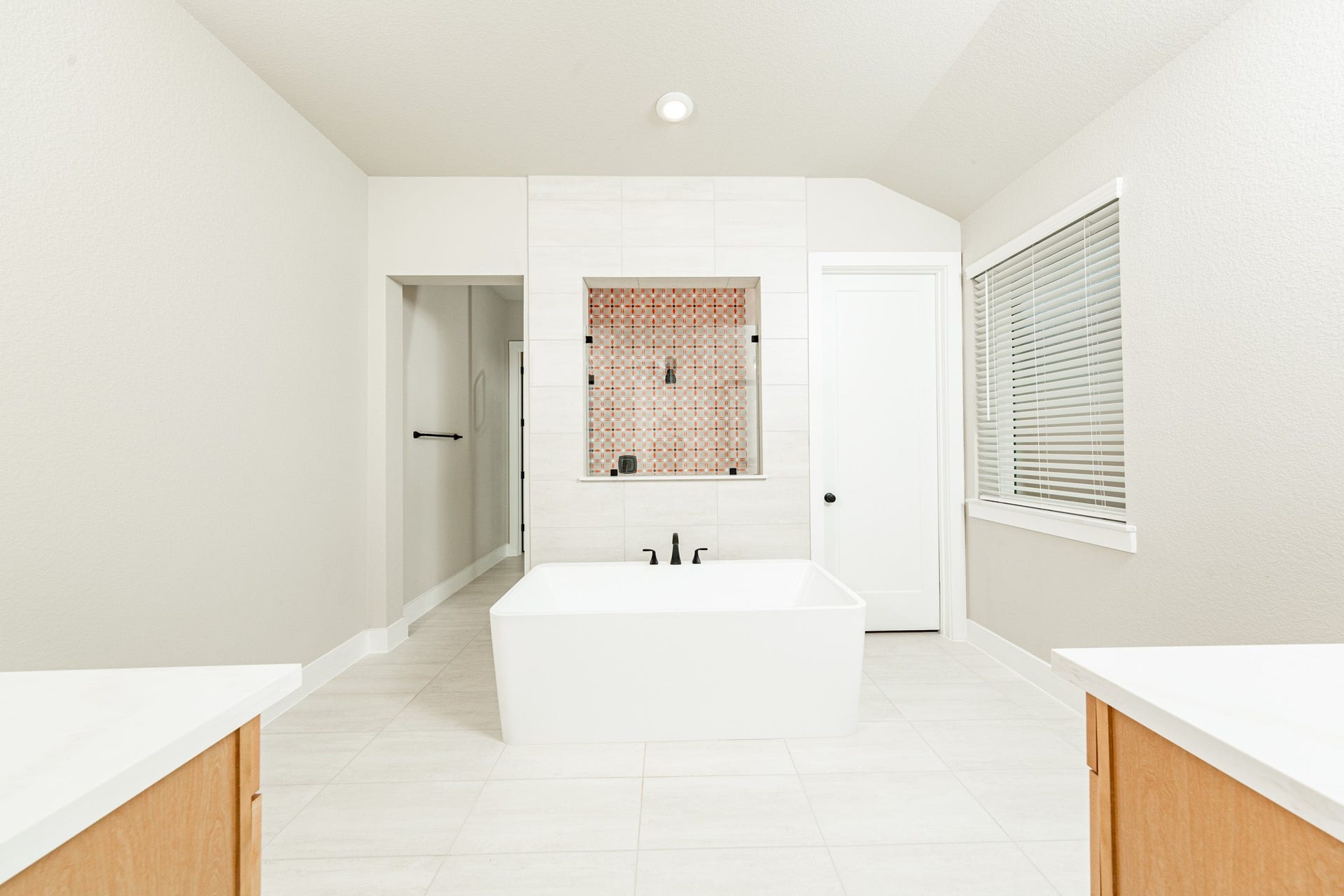 41418 Threadgill Way, Montgomery, TX 77316 The centerpiece of this contemporary primary bath is the deep, freestanding bathtub with gorgeous tile flooring, offering an ideal spot for relaxation with a unique view into the walk-in shower.