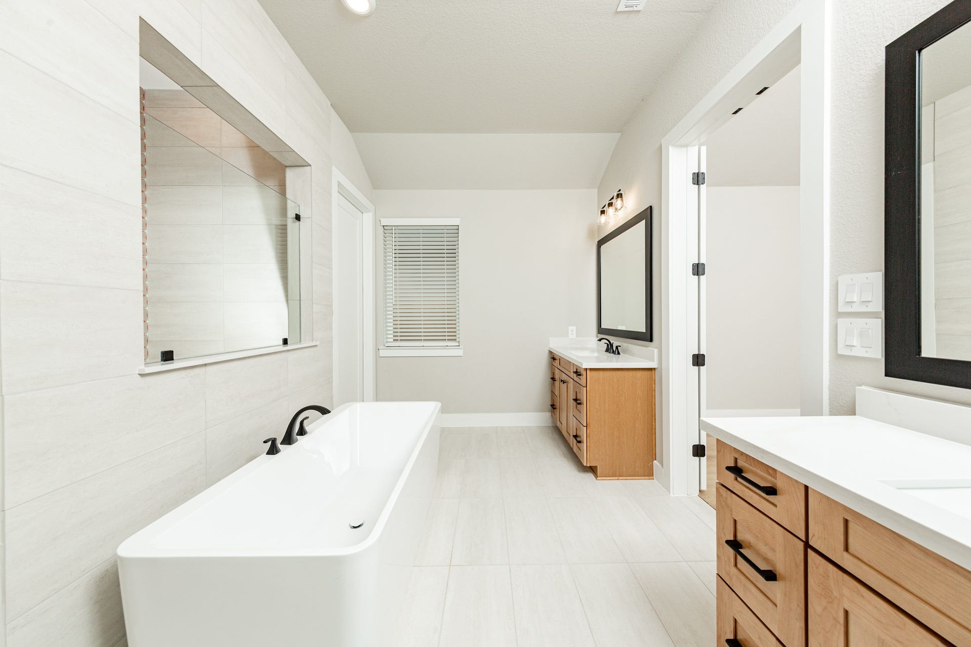 41418 Threadgill Way, Montgomery, TX 77316 Modern primary bath features dual vanities with sleek white cabinetry, a quartz countertop, framed vanity mirrors, and black matte fixtures for a truly contemporary feel.