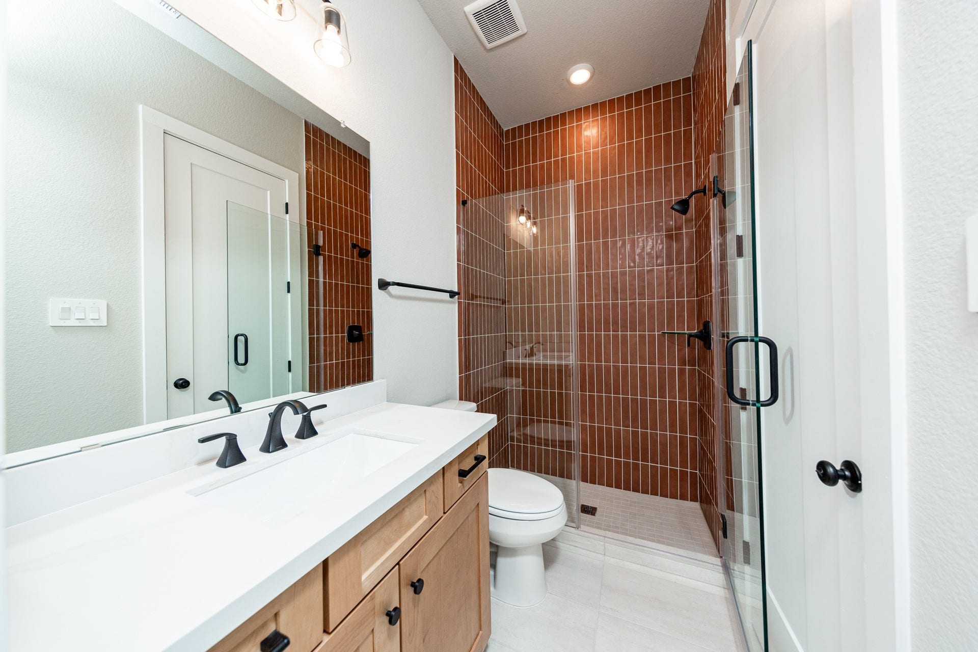 41418 Threadgill Way, Montgomery, TX 77316 This ensuite secondary bathroom features a modern vanity, large walk-in shower with gorgeous modern tile surround, and modern black matte finishes.