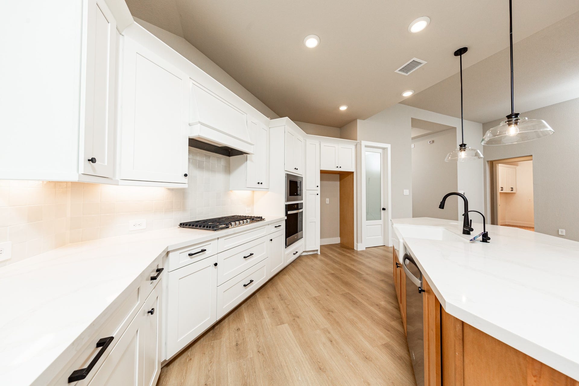41418 Threadgill Way, Montgomery, TX 77316 A spacious central island offers prep space and houses a sleek farmer's sink and a dishwasher. Recessed and contemporary pendant lights ensure a well-lit environment.