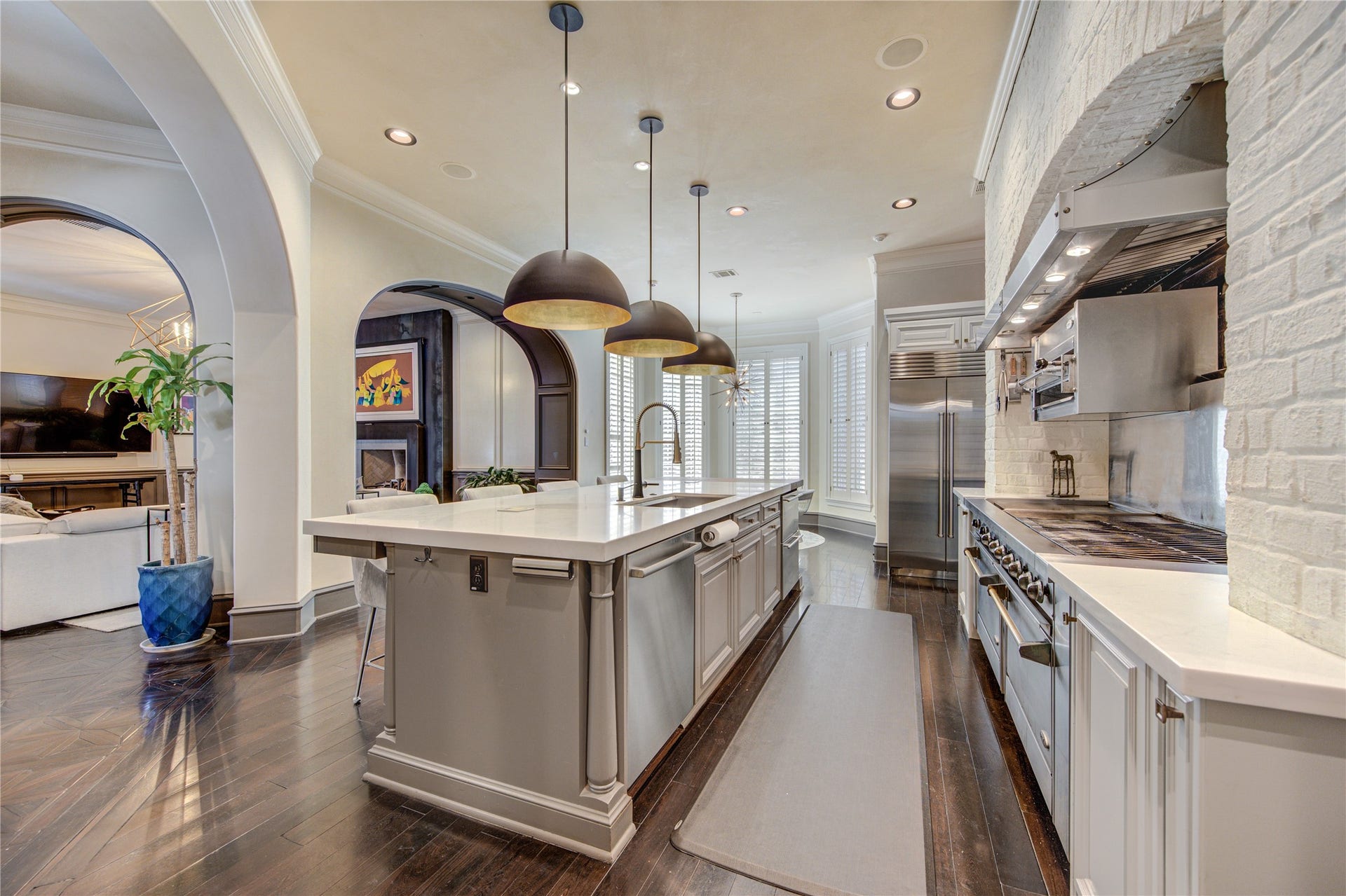 5110 W Oak Mews, Houston, TX 77056 The gourmet kitchen offers a stunning perspective toward the inviting living room, showcasing its open-concept design and effortless flow for entertaining. Custom cabinetry beautifully conceals the built-in Sub-Zero refrigerator, while premium finishes and thoughtful craftsmanship create a sophisticated space where luxury and functionality come together.