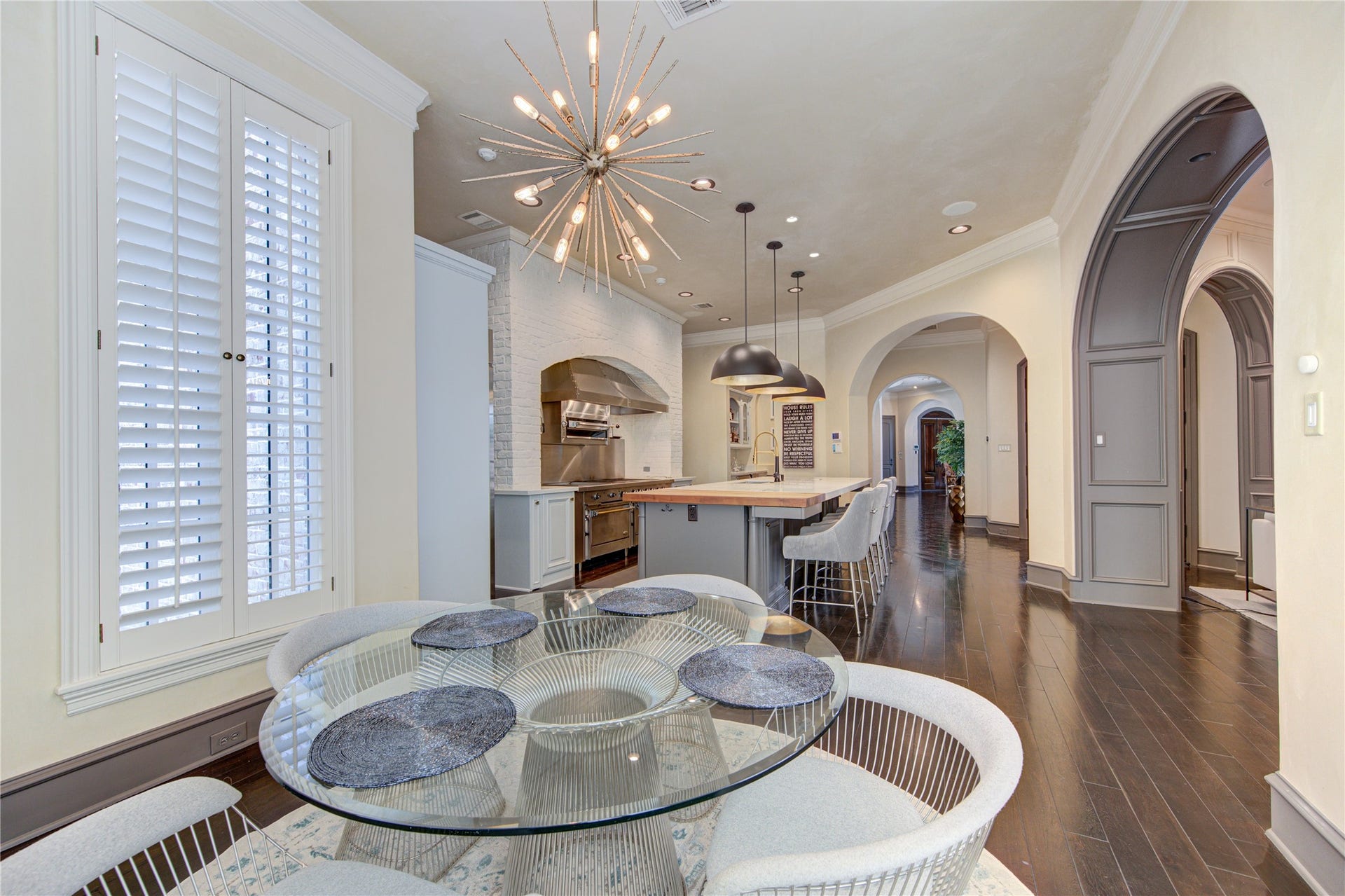 5110 W Oak Mews, Houston, TX 77056 The sunlit breakfast room is an inviting space to begin the day, featuring striking modern lighting set against timeless European-inspired architecture. Graceful arches, rich wood paneling, and refined craftsmanship create a warm yet sophisticated atmosphere, blending classic elegance with contemporary design for everyday dining and intimate gatherings.