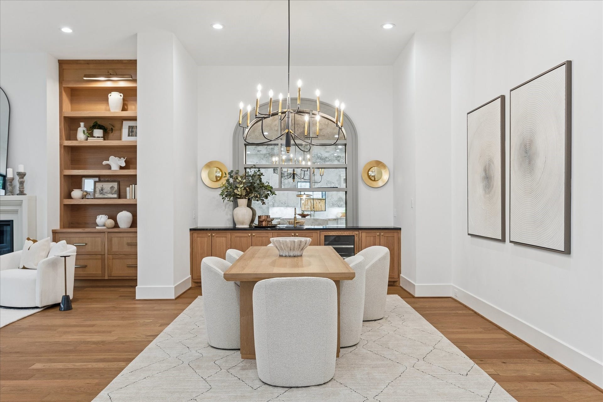 Warm oak cabinetry and soft gold sconces create a refined dining alcove, anchored by an arched mirror that introduces architectural depth. The space feels intimate yet connected to the homes broader entertaining areas. *Previous Project*