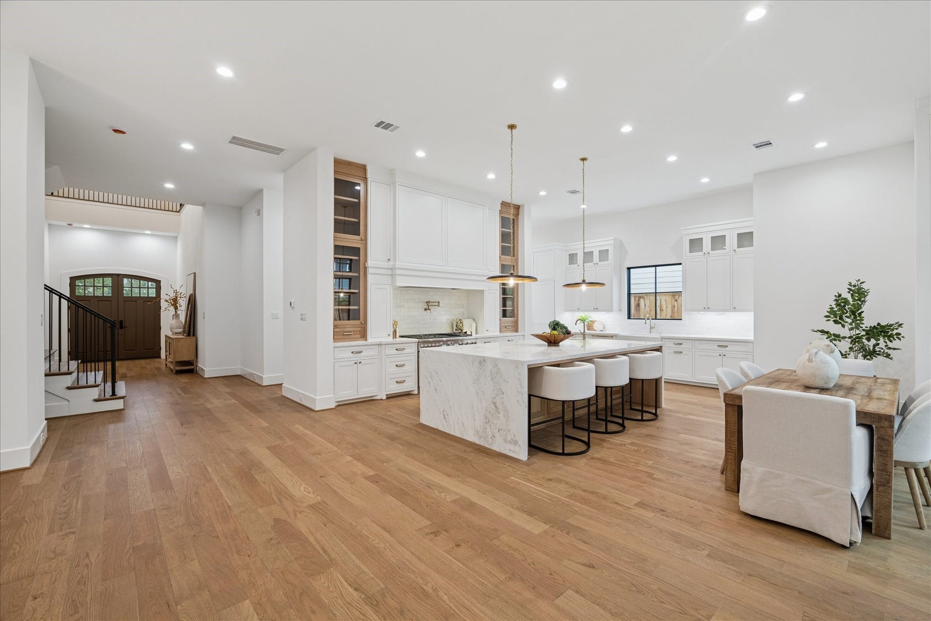 A dramatic marble waterfall island anchors the gourmet kitchen, paired with floor-to-ceiling custom cabinetry, sculptural hood design, and warm oak accents. Thermador appliances elevate the cooking experience, while pre-plumbing for a future water softener and Generac system supports long-term convenience. Brass details and architectural millwork reflect the homes refined aesthetic and modern functionality. *Previous Project*