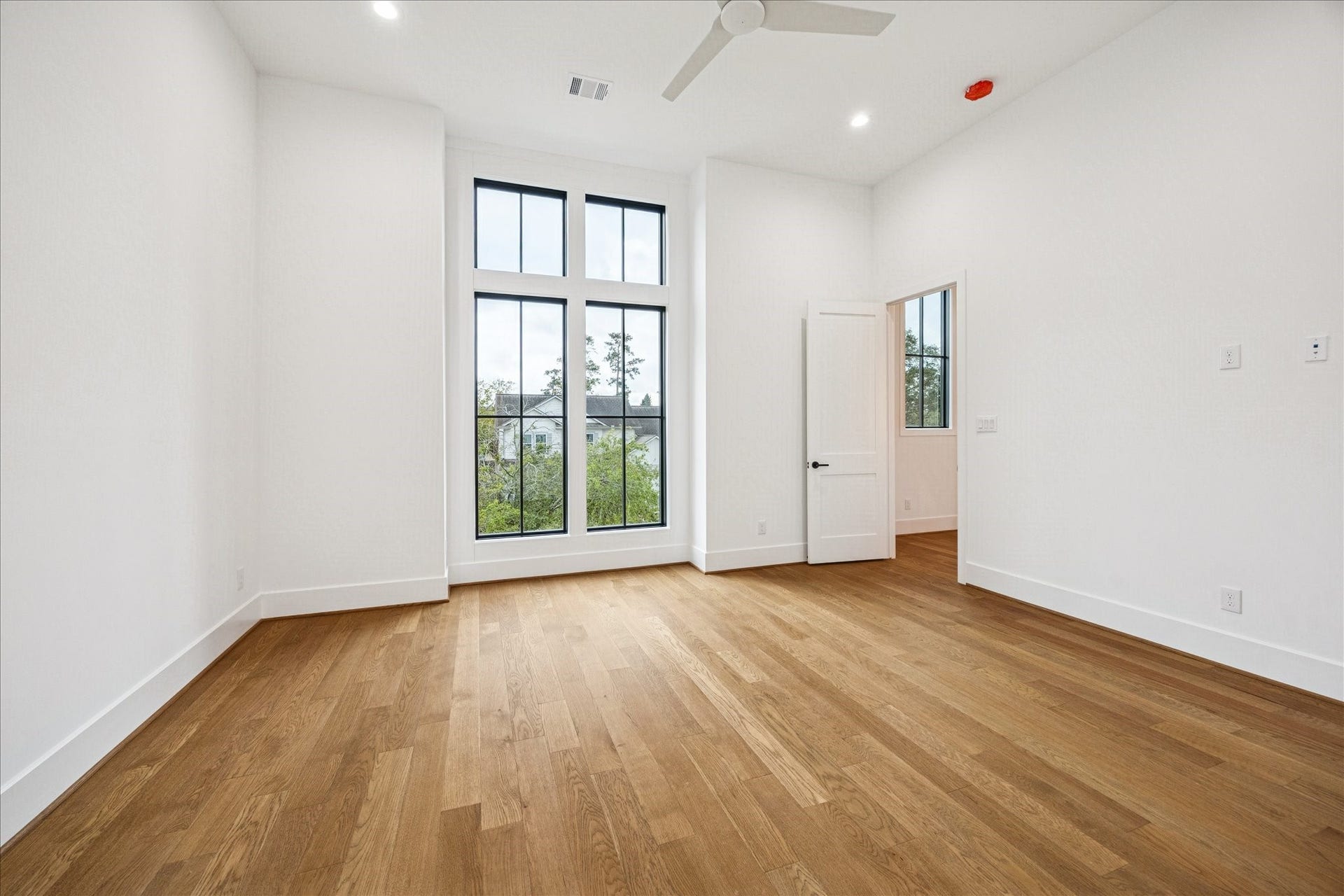 Sunlight pours through the vertical window set, creating an airy retreat ideal for a secondary suite or guest room. Oak flooring and smooth walls enhance the serene feel. *Previous Project*