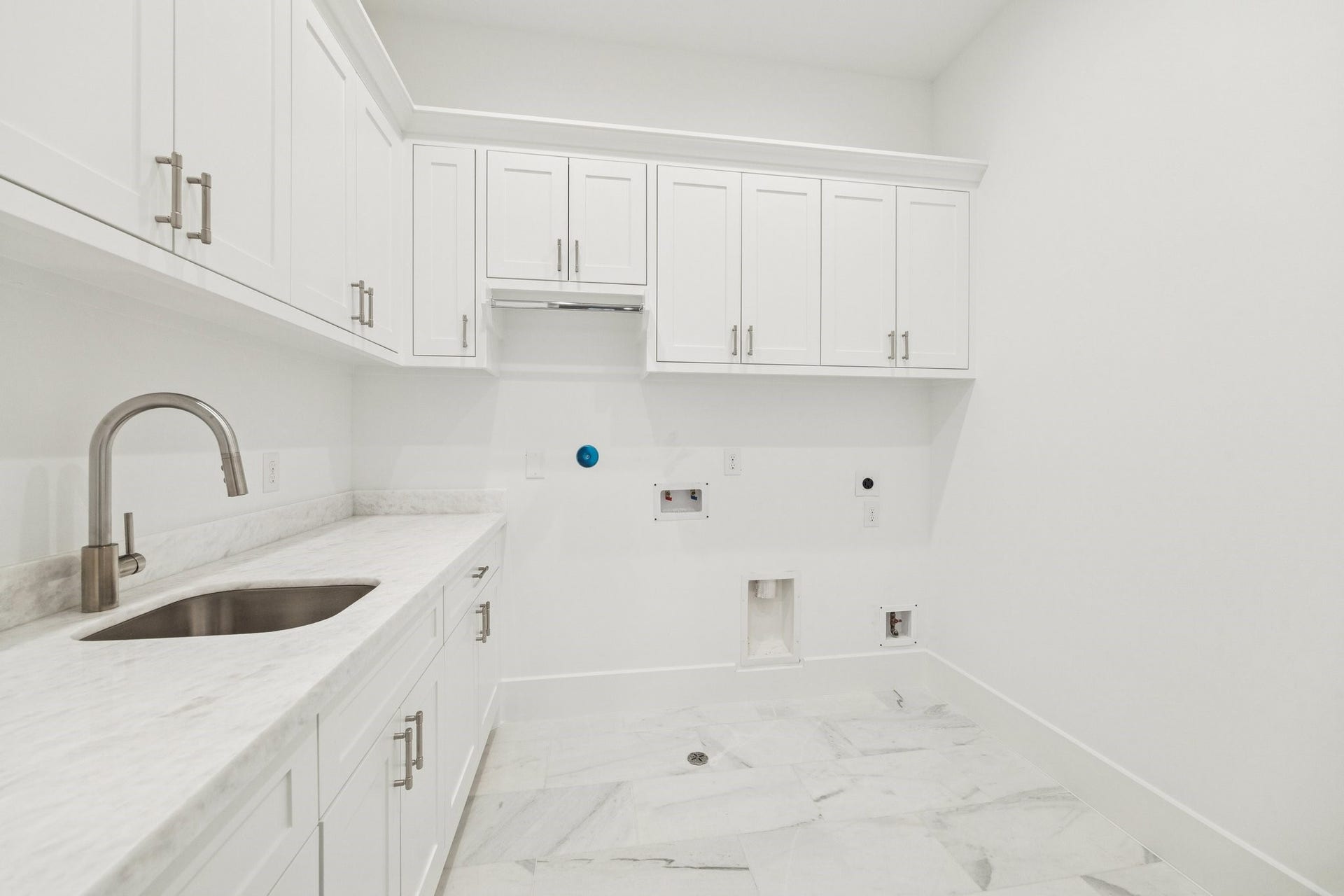 This well equipped utility room combines functionality with clean design, showcasing abundant cabinetry, a dedicated sink area, and plenty of room for laundry essentials and everyday storage. *Previous Project*