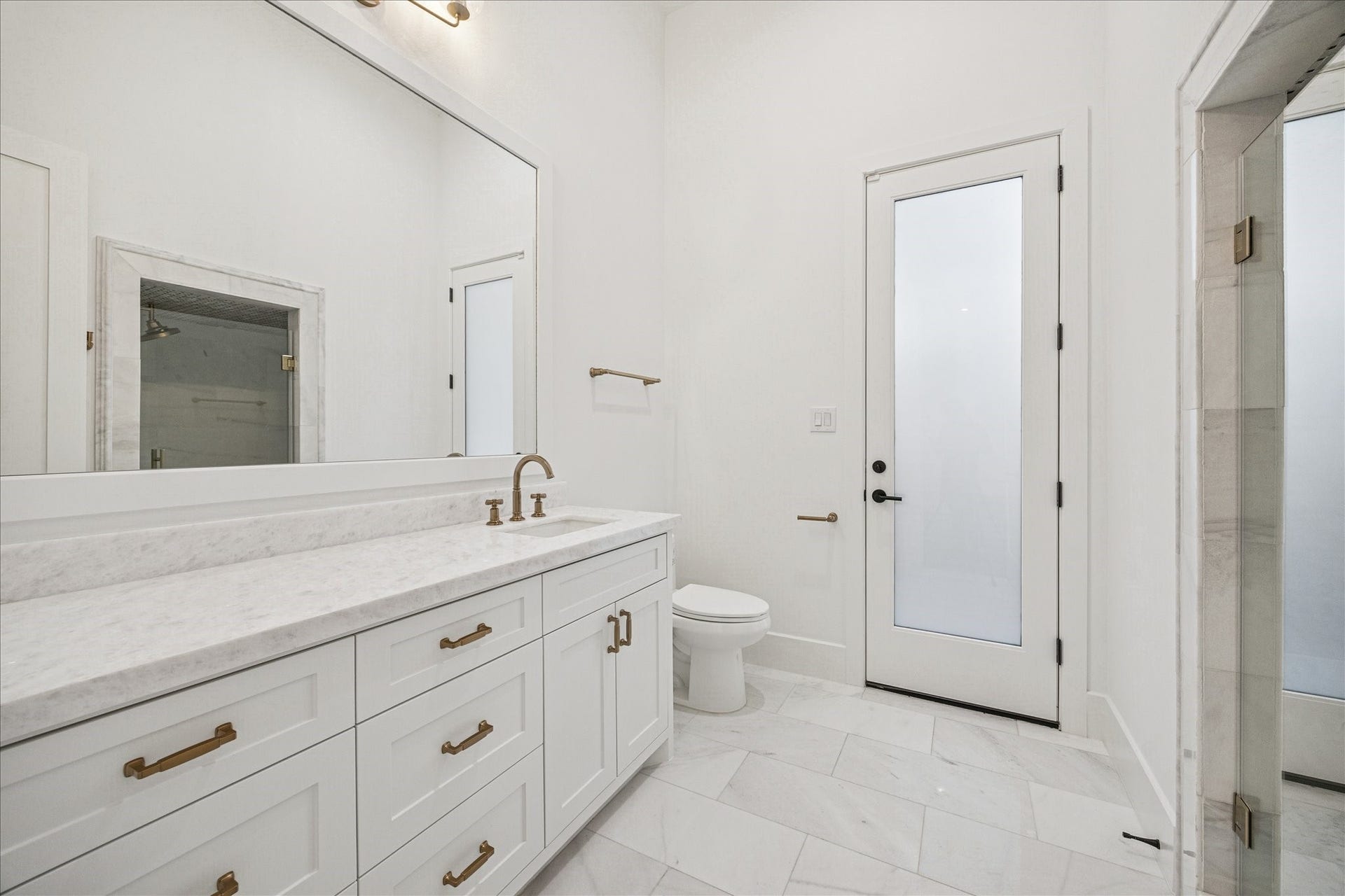 Located off the main staircase with direct outdoor access, the pool bath features marble finishes, brass fixtures, and a freestanding shower. Guests can enter from outside, preserving the homes main living spaces during pool days or entertaining. *Previous Project*