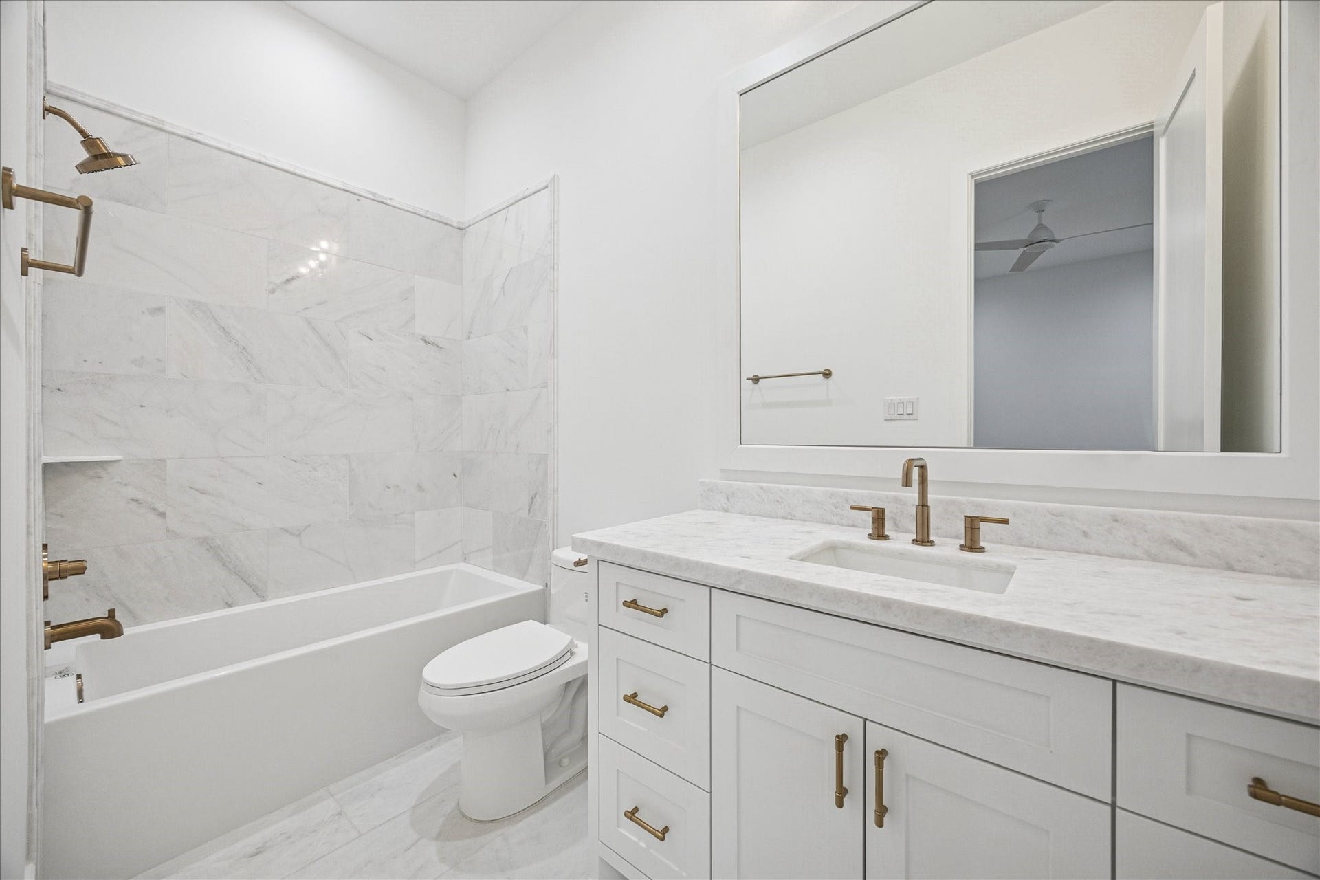 A modern bath with marble pattern tile, shaker cabinetry, brass hardware, and a full-size tub. Large-format flooring and soft white walls keep the space bright and calming. *Previous Project*