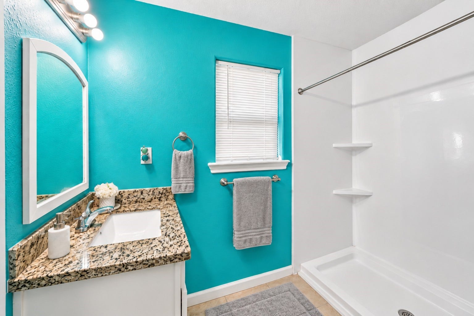 A pop of color brightens this full bathroom, featuring granite countertops and a spacious step-in shower.