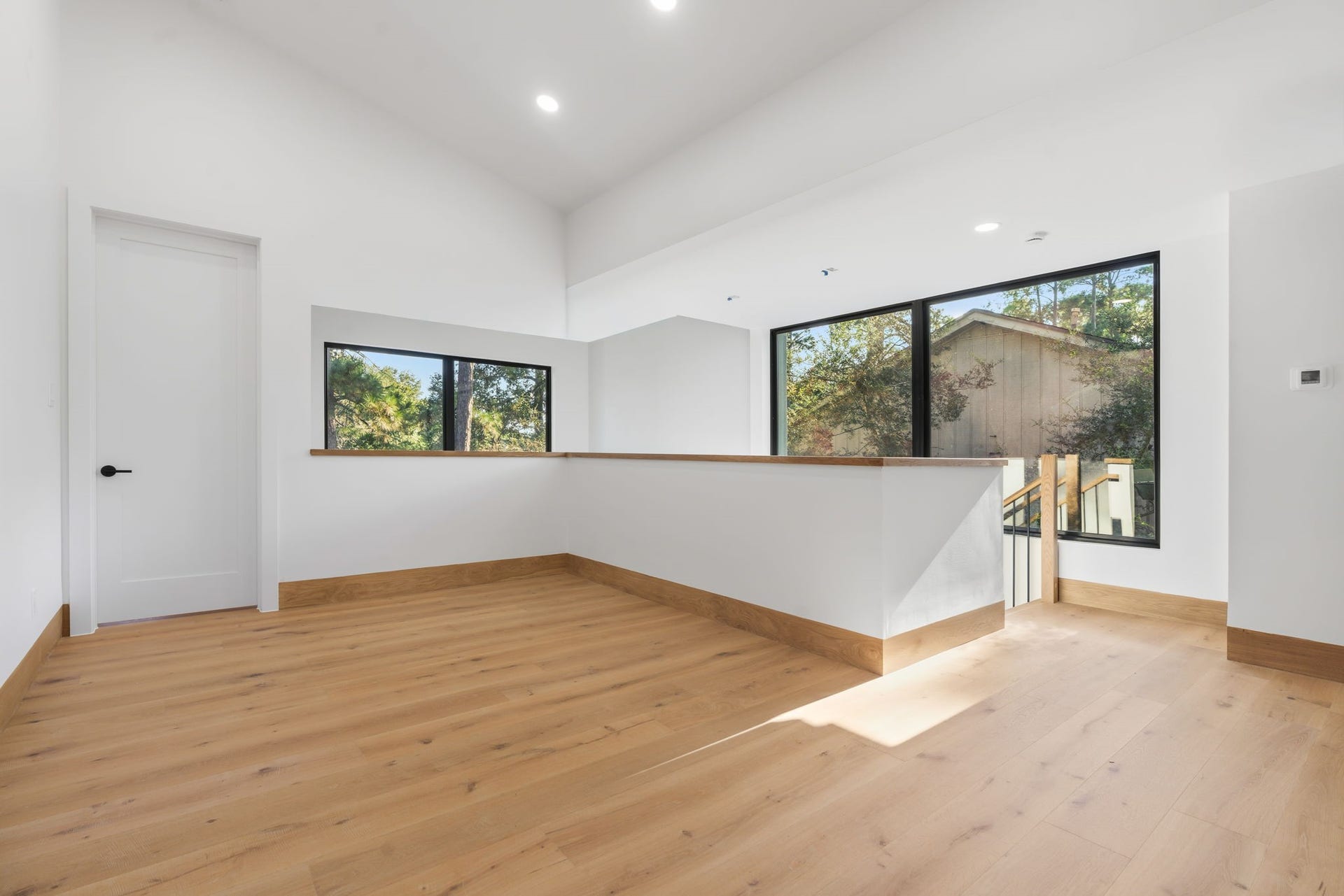 12 N Timber Top Dr, Spring, TX 77380 Spacious second-floor game room / sitting area featuring high ceilings, warm wood flooring, and large windows that fill the space with natural light