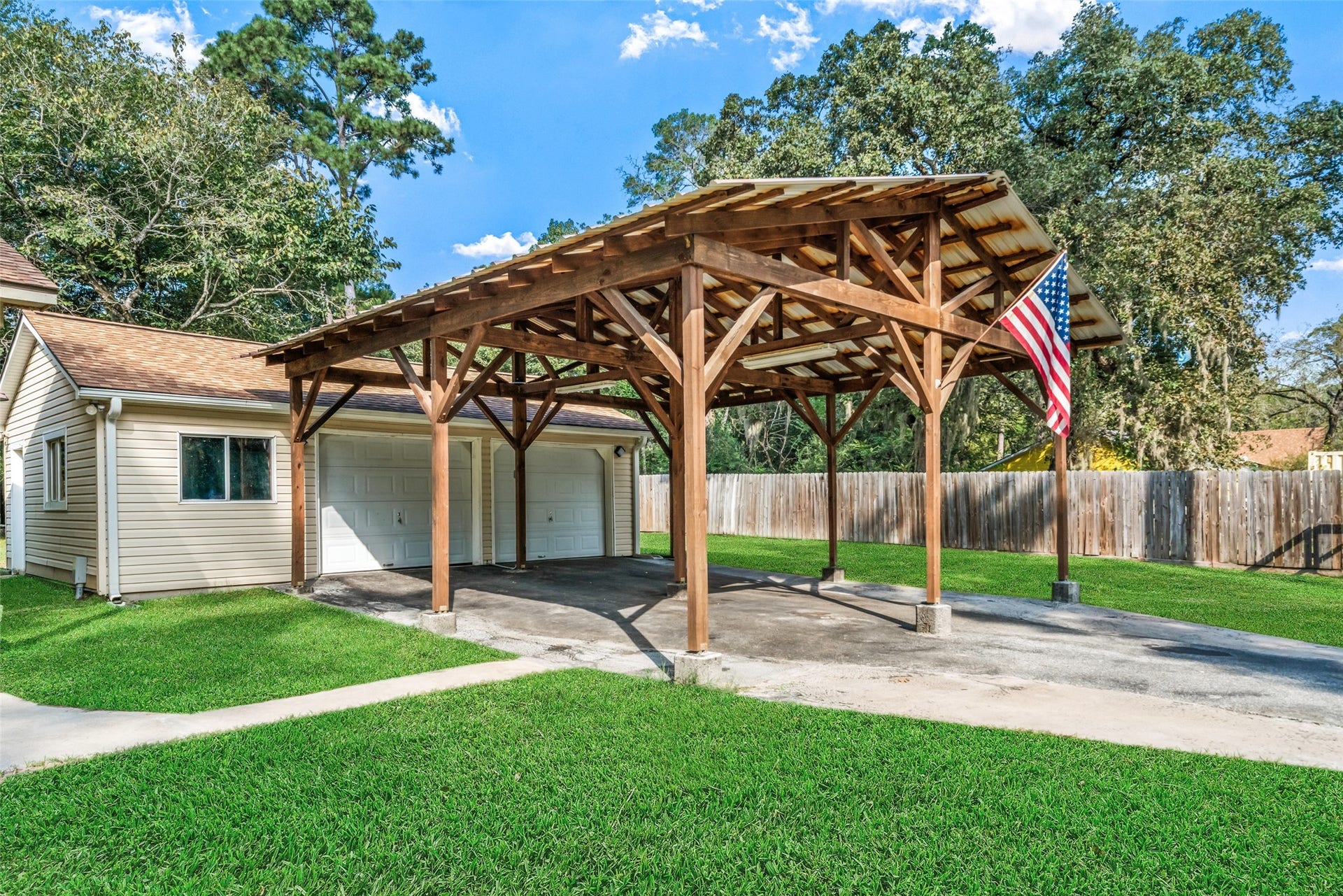 The garage (approx. 600 sqft) offers front and rear roll-up doors, making it ideal for easily pulling through or parking recreational vehicles or storing equipment. It includes a workshop area complete with benches and cabinets, providing a space for projects, storage, and tools. Measuring 2222, this mega carport features a soaring structure with the lowest beam around 10.5 feet high, allowing clearance for tall vehicles, boats, or oversized equipment. It is fully lighted and includes an electrical outlet.