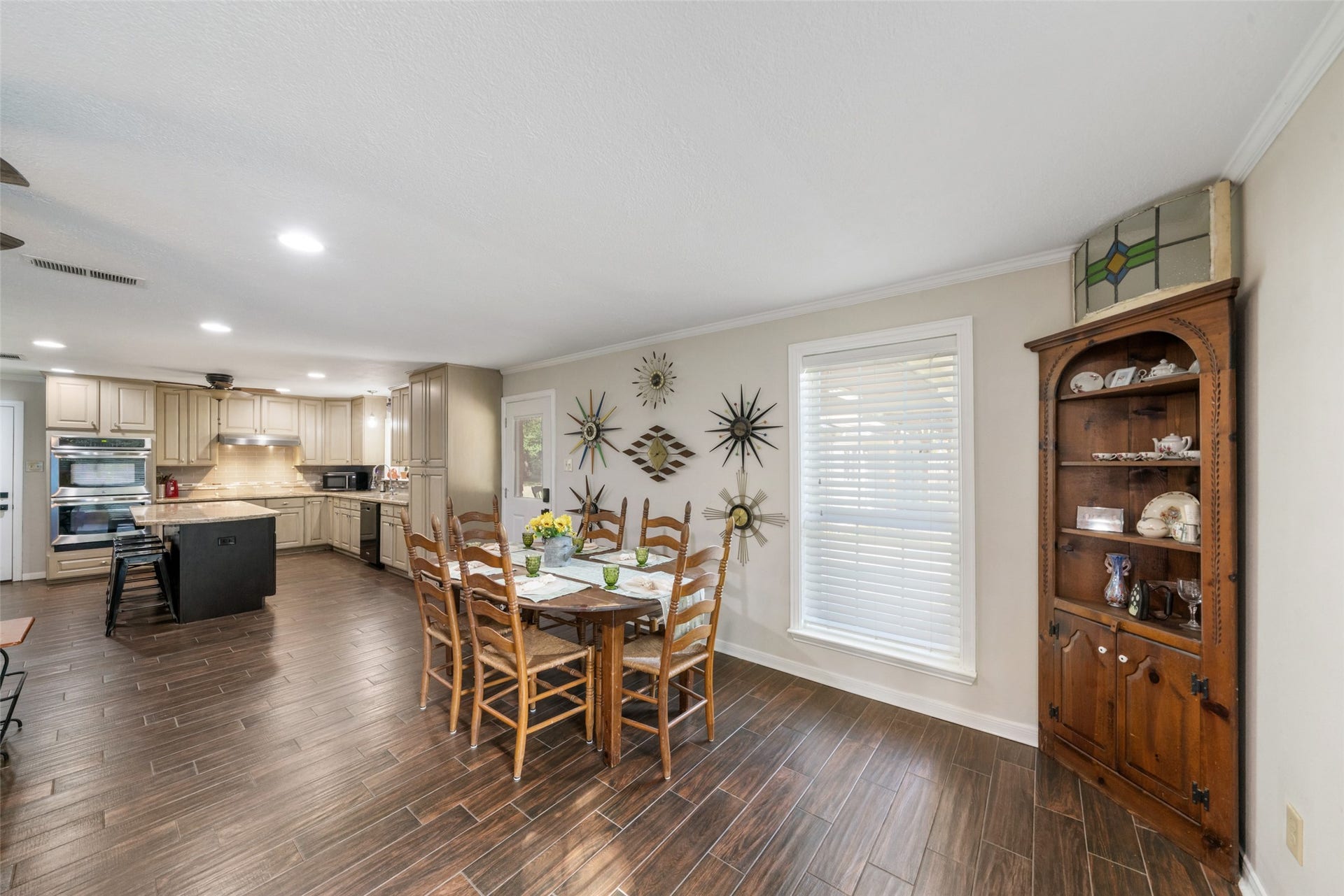 The dining area is warm, bright, and perfectly positioned at the heart of the home. Natural light pours in through the large window that looks out to the covered patio, highlighting the rich wood-look flooring and creating an inviting atmosphere for everyday meals or special gatherings. The space offers generous room for a full-size dining table and has a seamless connection to the kitchen. Its open flow makes serving, entertaining, and family time effortless.