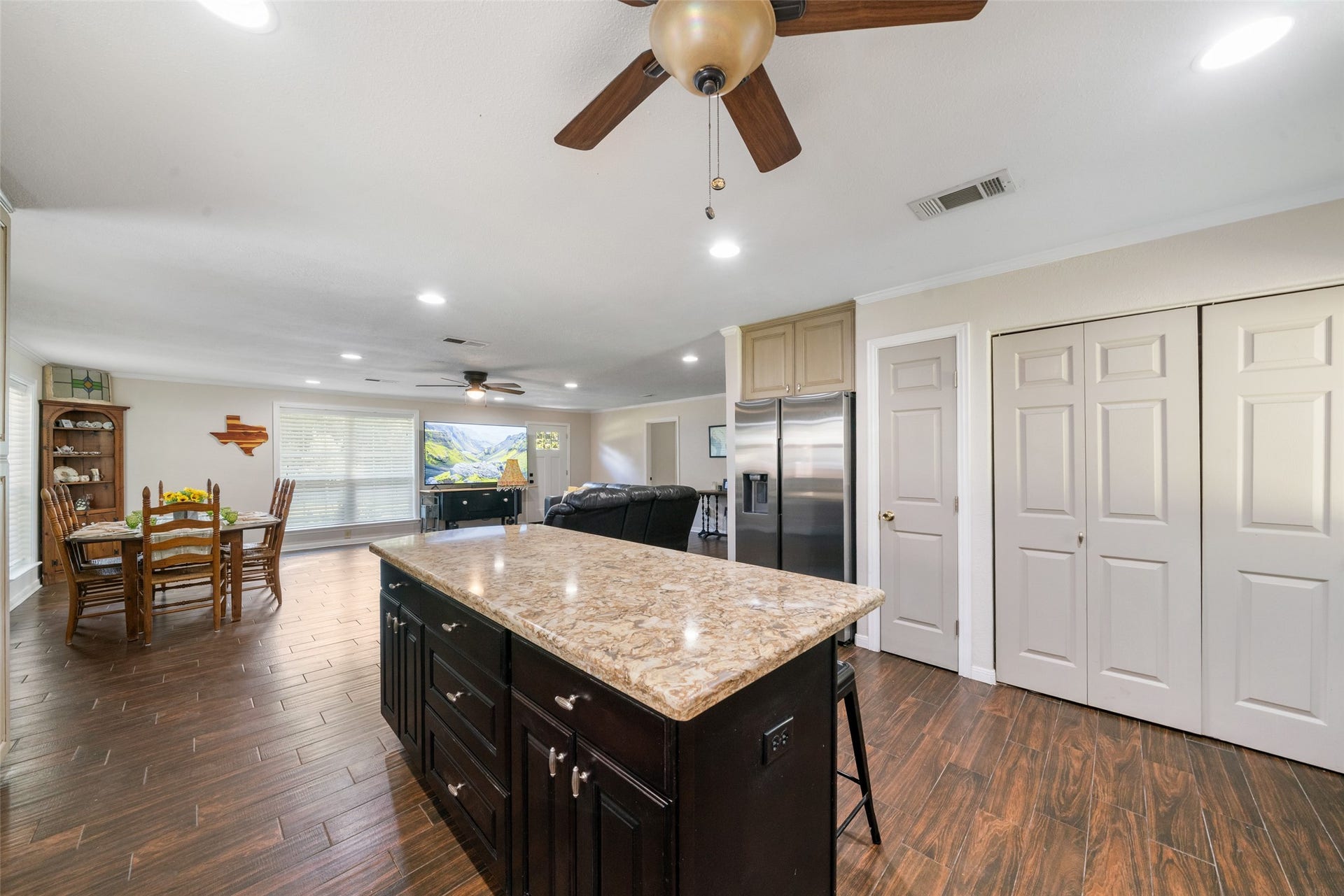 Cooking, watching TV, and doing laundry all at the same time, its absolutely possible in this well-designed layout. The small door leads to the pantry, and the laundry room is conveniently located behind the double folding doors, making everyday tasks easy and accessible. And yes, the stainless-steel refrigerator stays with the home, adding even more value to this fantastic setup.