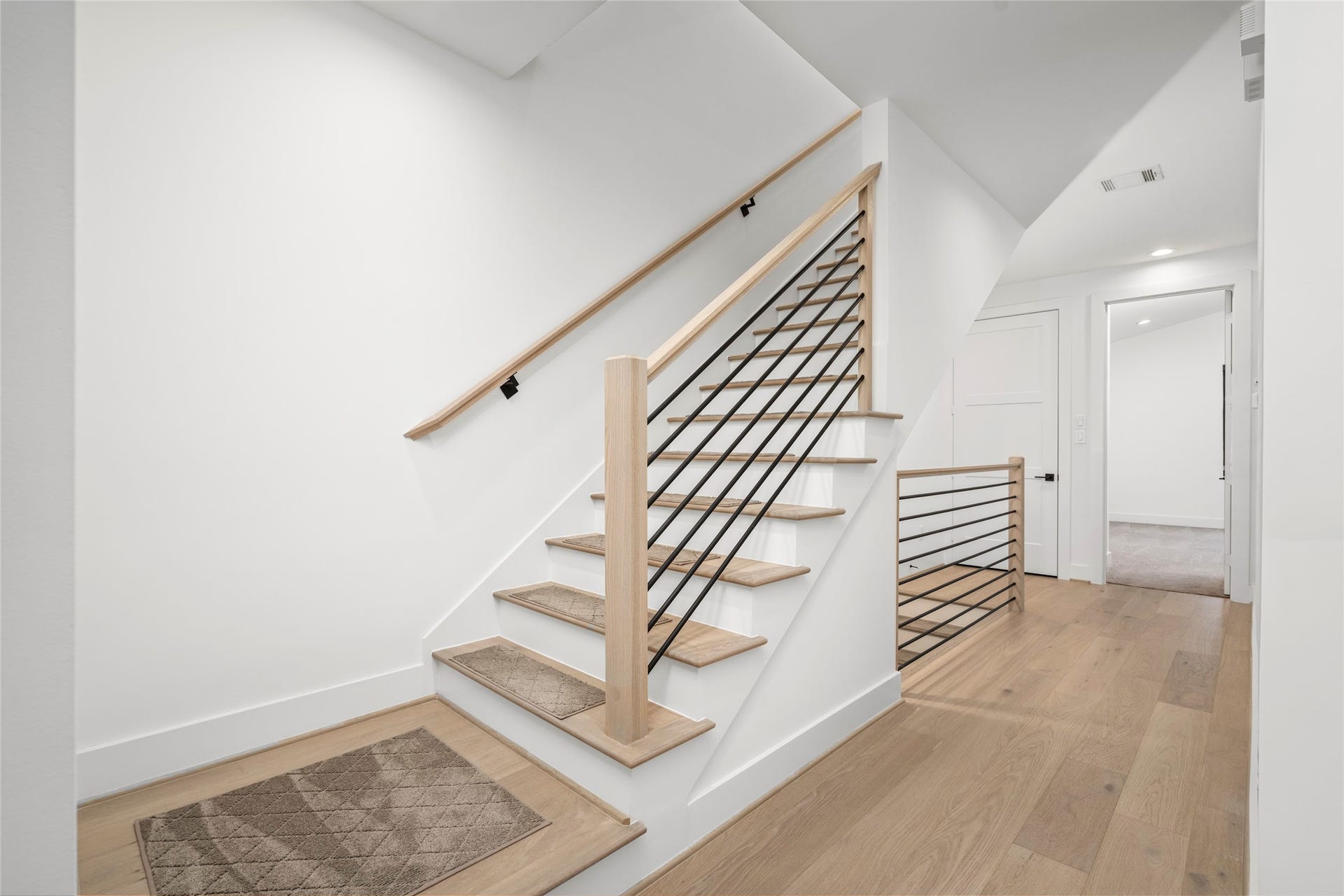 2410 Elmen Street, Houston, TX 77019 A view of the staircase between the second and third floors. Transitional iron balusters, wood handrails and newel posts. Engineered wood steps and painted risers.