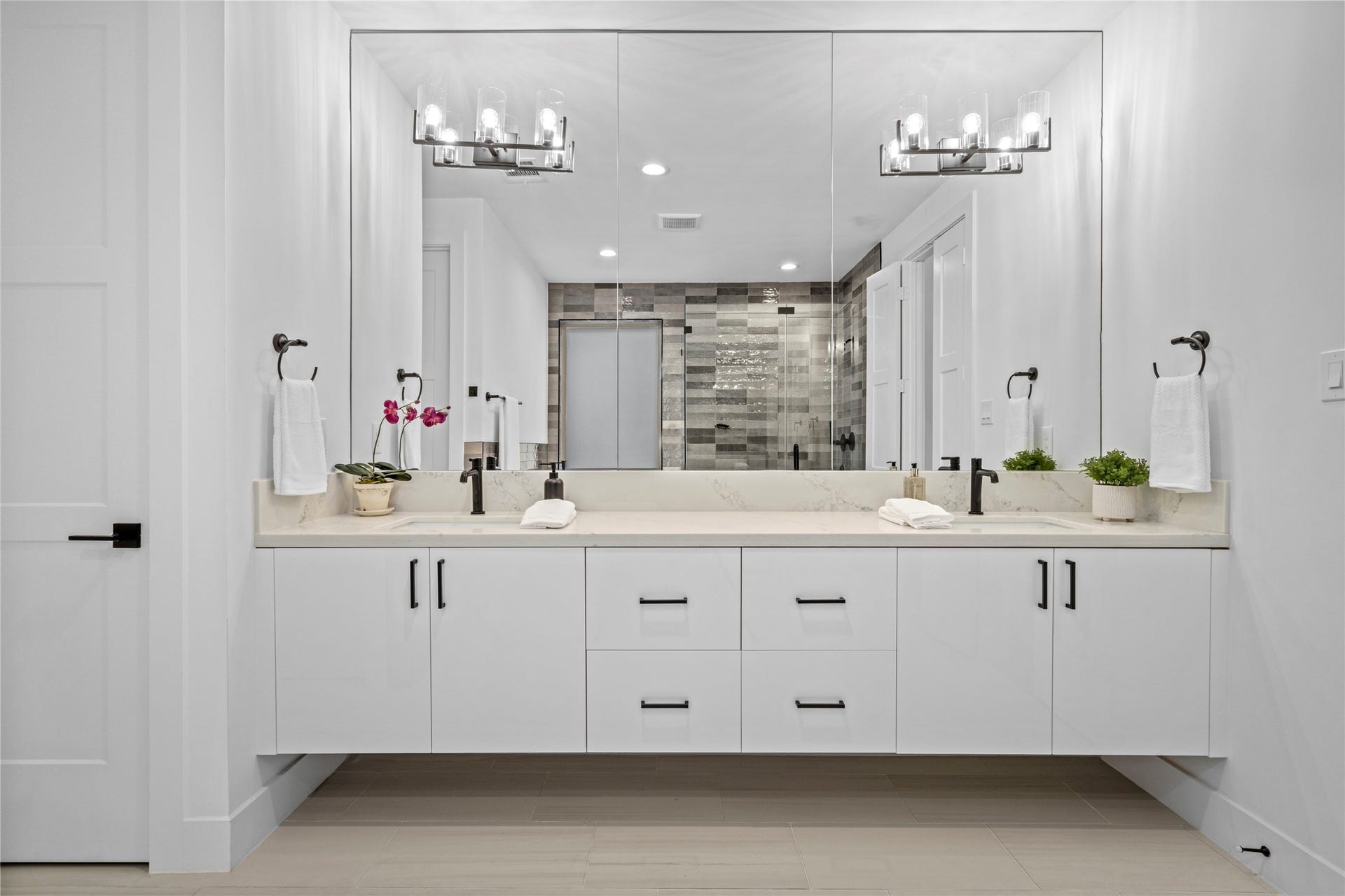 2410 Elmen Street, Houston, TX 77019 The double vanity has undermount sinks, single lever faucets and triple light sconces. All fixtures, hardware and bath accessories have matte black finish.