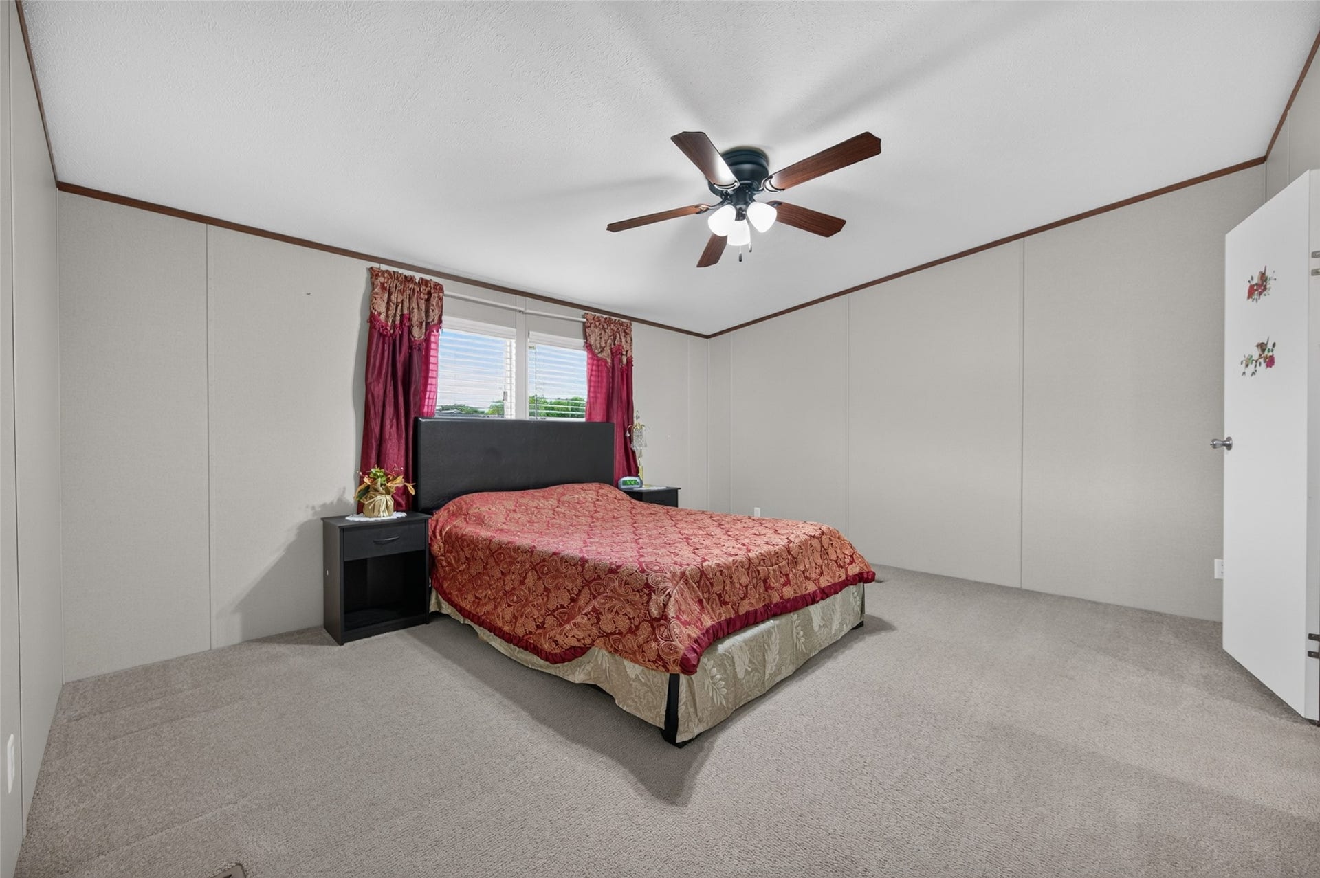 Spacious primary bedroom with plush carpet and a ceiling fan