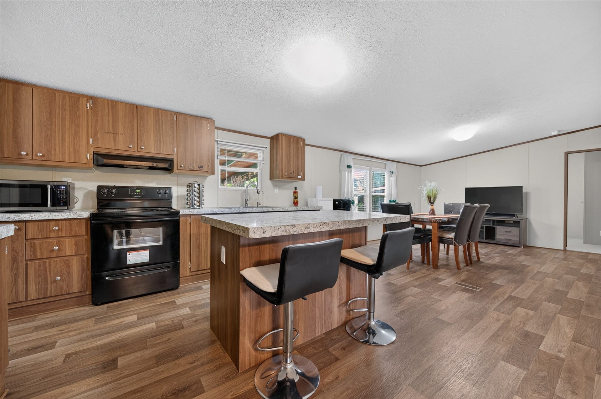 Kitchen island view with electric range and easy flow into the living area
