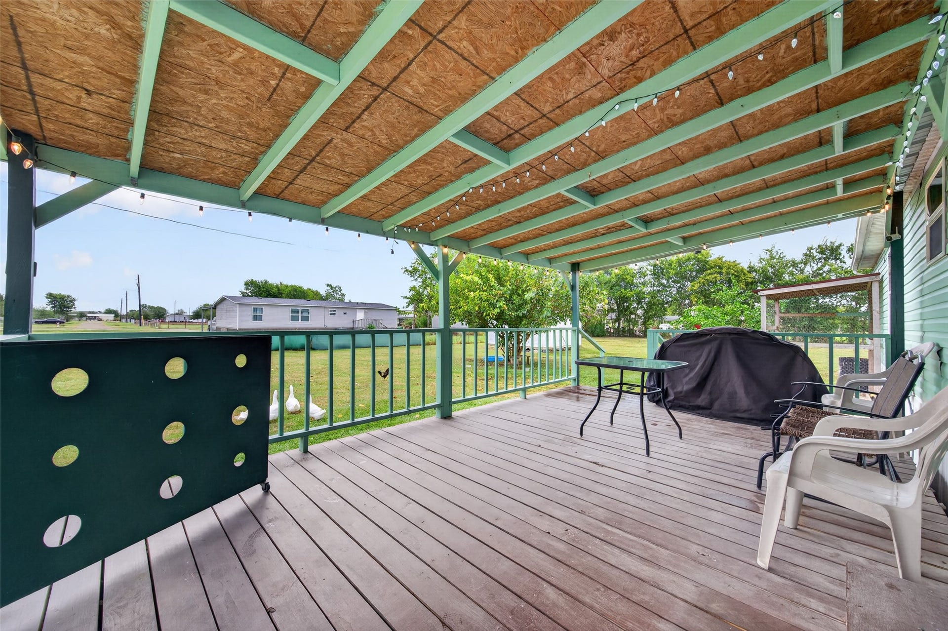 Covered back deck perfect for grilling and outdoor dining, with string lights for evening ambiance