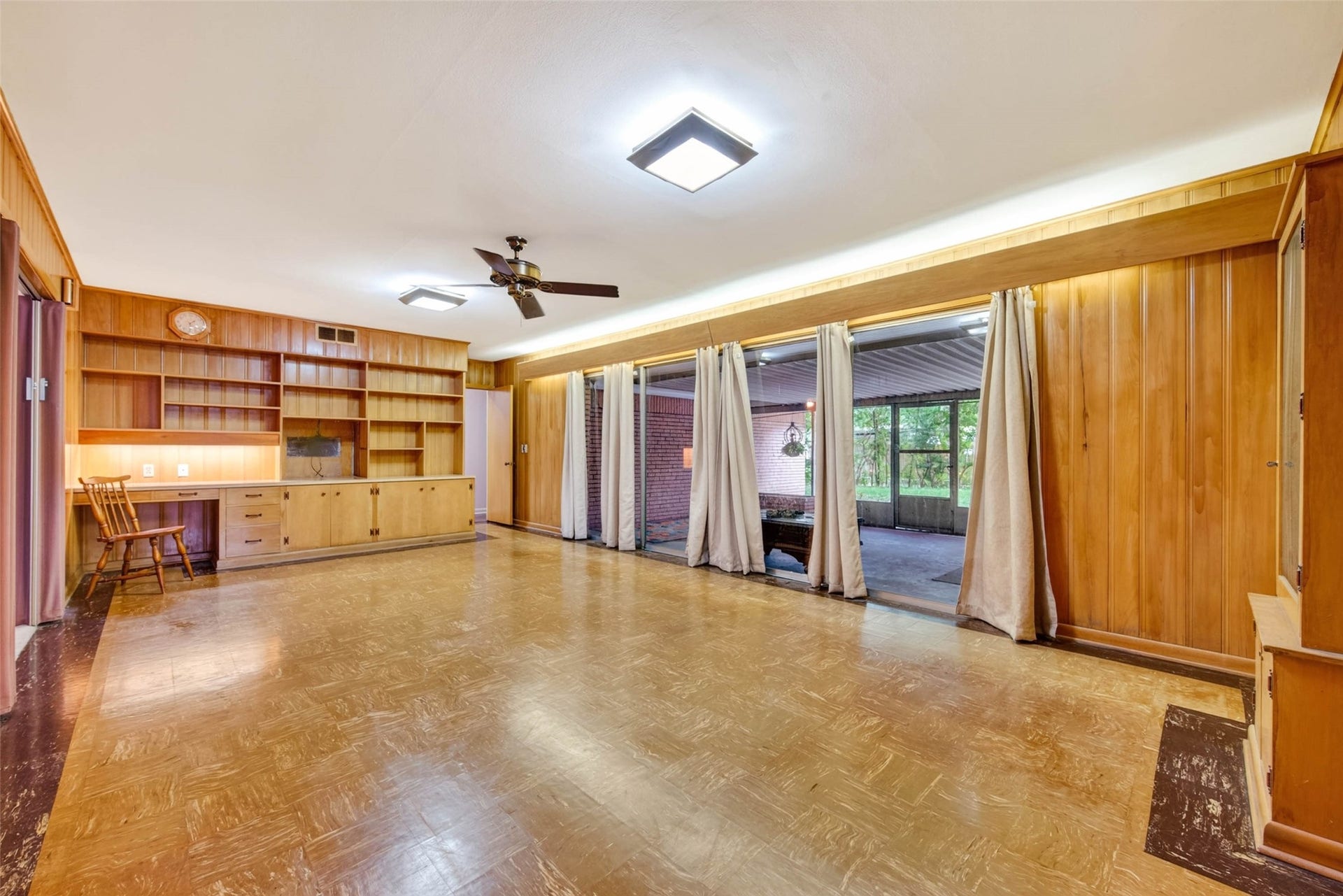 Den with view of built in desk and shelving