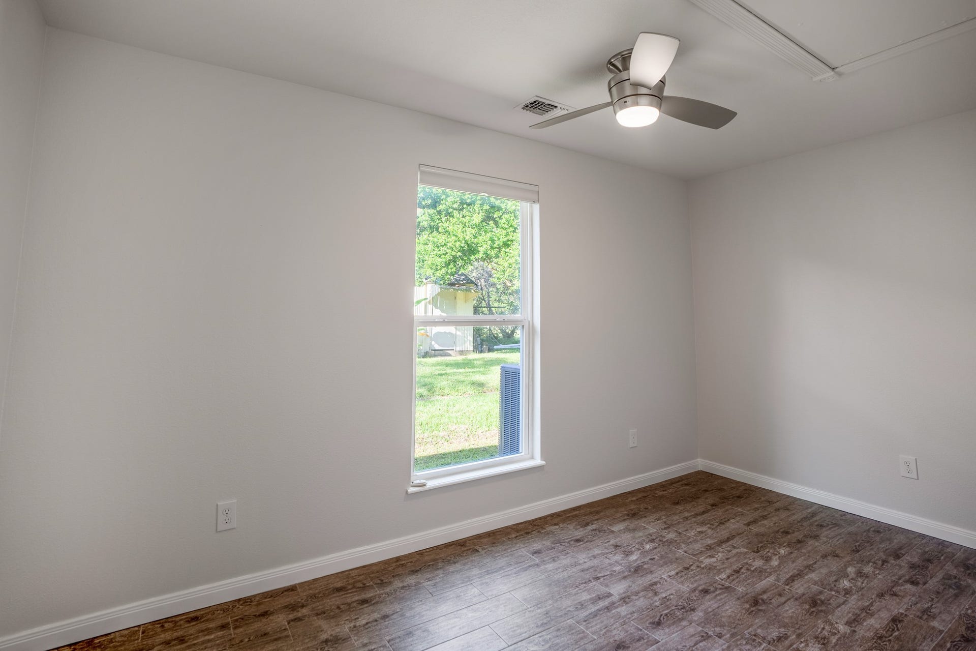 306 Foster Street, Tomball, TX 77375 Continuing down the hallway, we arrive at one of the two bedrooms toward the back of the home. A large window brings in natural light & offers a view of the side yard, while neutral walls & a ceiling fan make it easy to personalize the space.