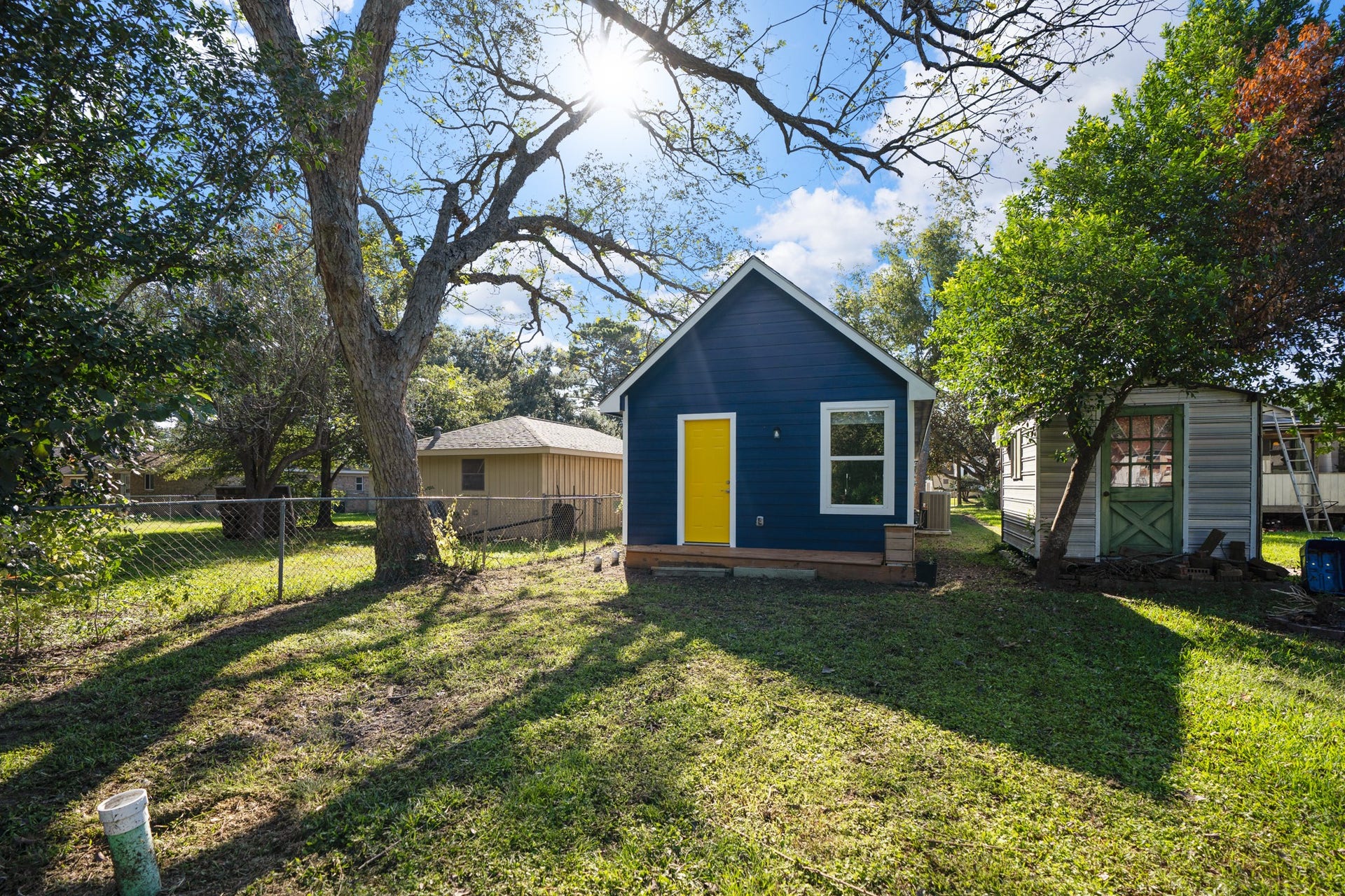 306 Foster Street, Tomball, TX 77375 Looking back toward the home from the backyard, mature trees provide plenty of shade over the grassy outdoor space. The raised deck offers direct access to the primary bedroom, while a storage shed provides additional room for outdoor equipment & more.