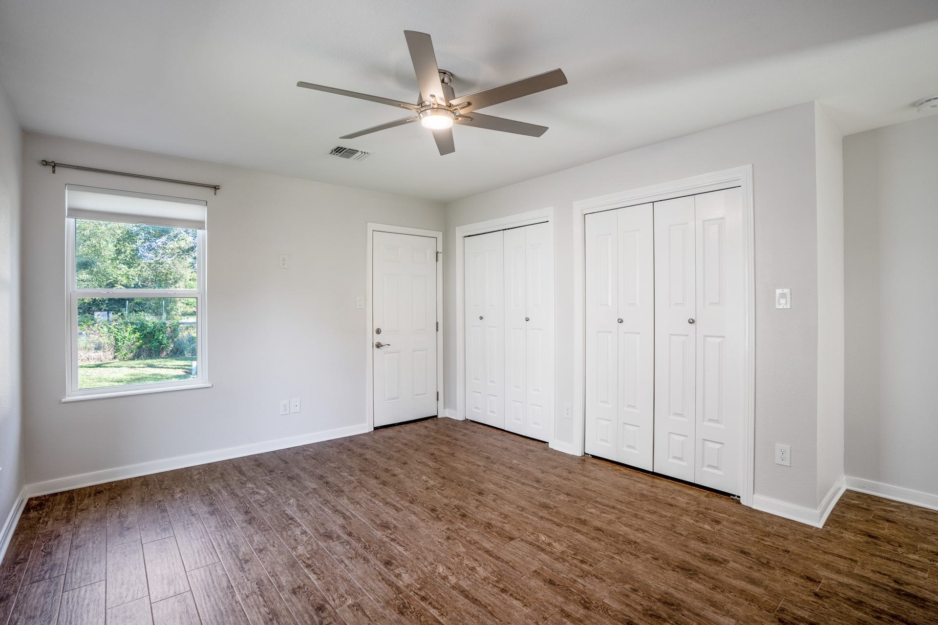 306 Foster Street, Tomball, TX 77375 Another view of the primary bedroom reveals TWO closets, offering plenty of storage for clothing, shoes & more! A large window overlooks the backyard, while the modern ceiling fan & neutral walls complete the space. The door (on the left) beside the closets provides direct access to the backyard.