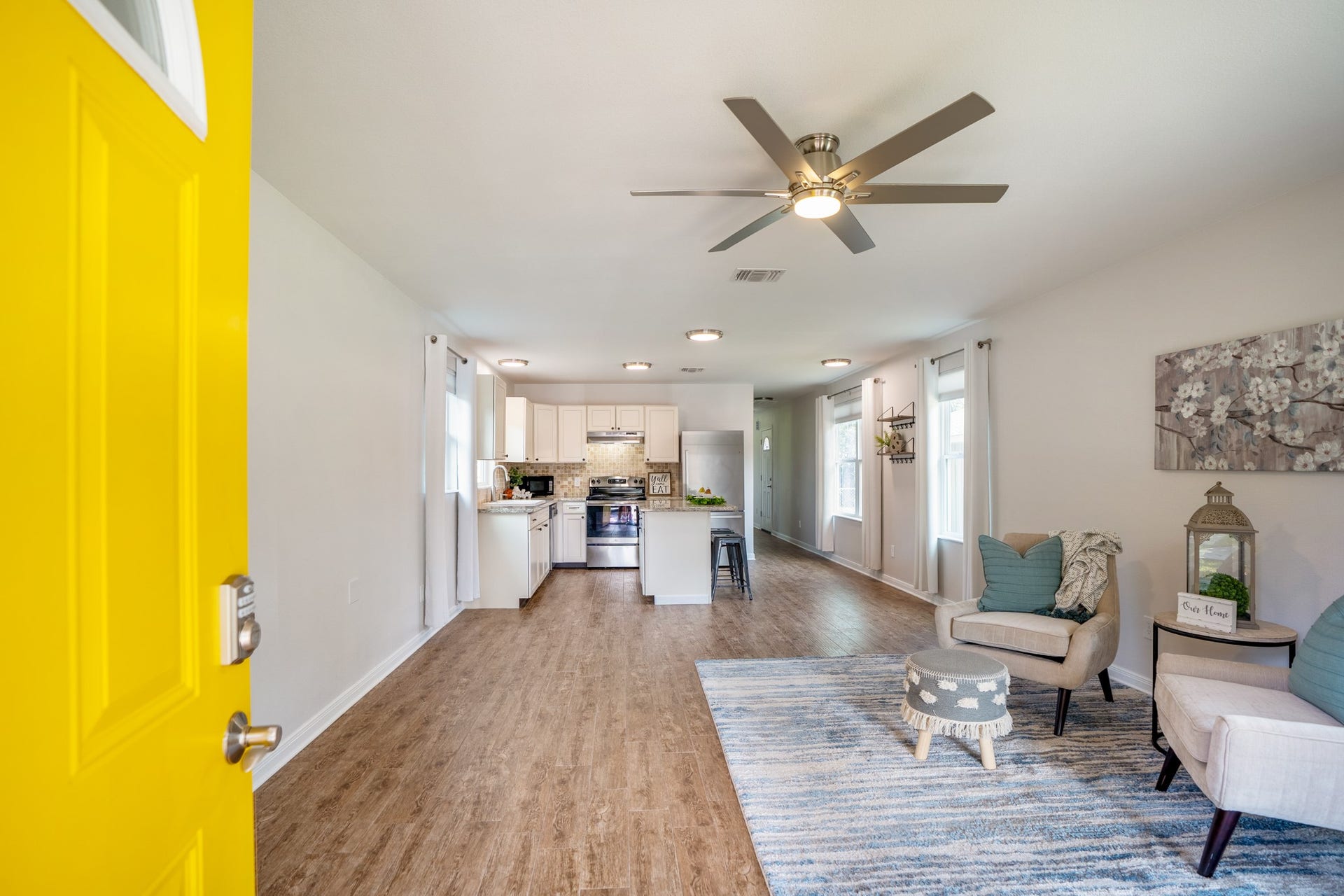 306 Foster Street, Tomball, TX 77375 Step inside, where the cheerful yellow front door opens directly into the spacious living room! Wood-look tile flooring runs throughout the open-concept living area, with plenty of natural light and the kitchen straight ahead. The layout makes it easy to enjoy both spaces, whether you're entertaining or enjoying a night at home.