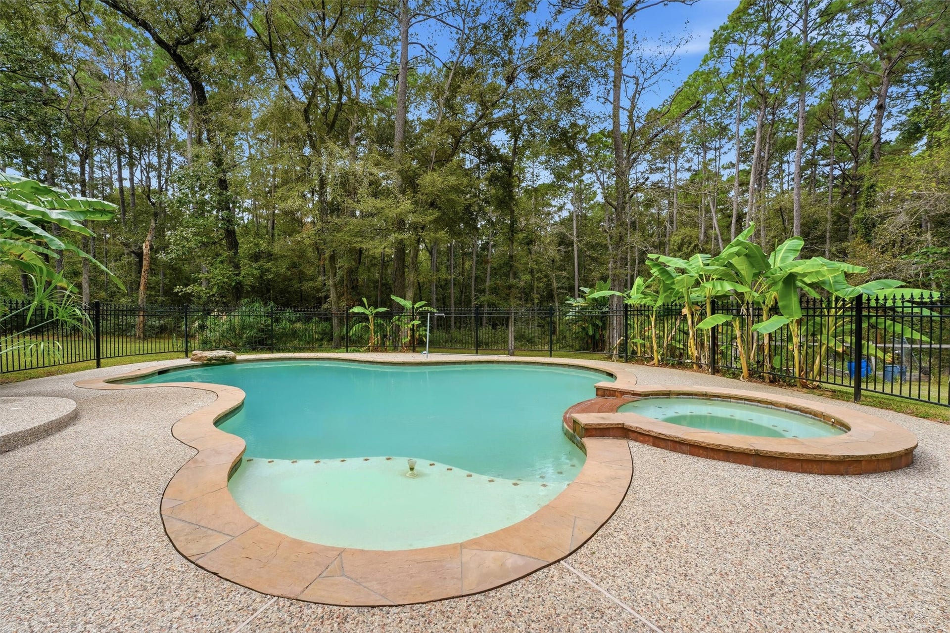 The swimming pool has attached hot tub, nestled in a private backyard surrounded by trees and lush landscaping.