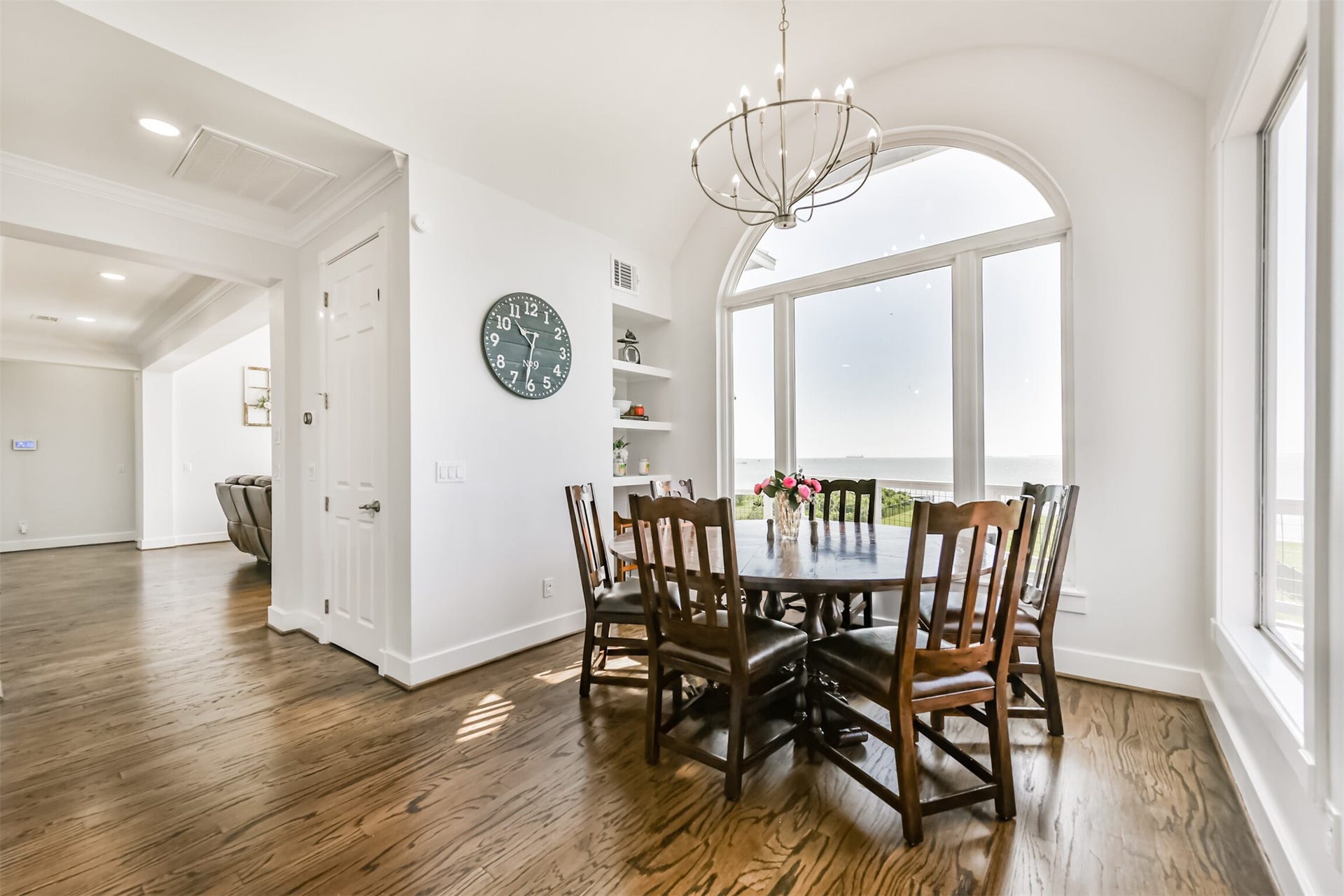 Dining area with a round table, chandelier, and large arched window offering stunning views.
