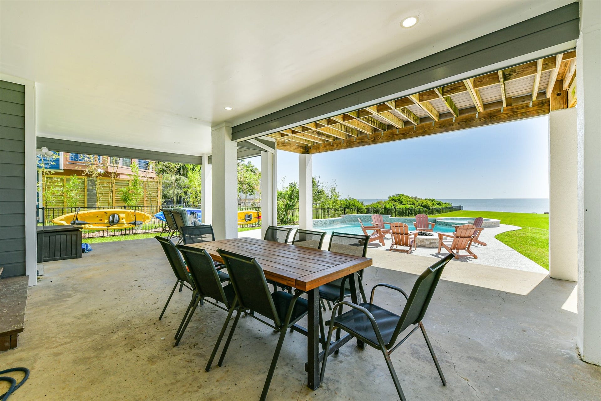 Spacious covered patio with a dining area overlooks a stunning pool and offers breathtaking ocean views, perfect for outdoor entertaining and relaxation.