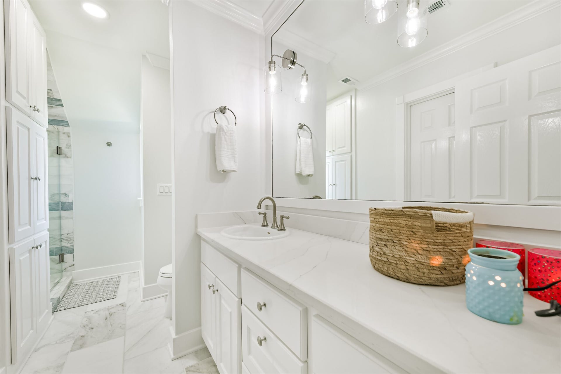 Elegant bathroom featuring a sleek white vanity with ample storage, modern fixtures, and a spacious glass-enclosed shower.