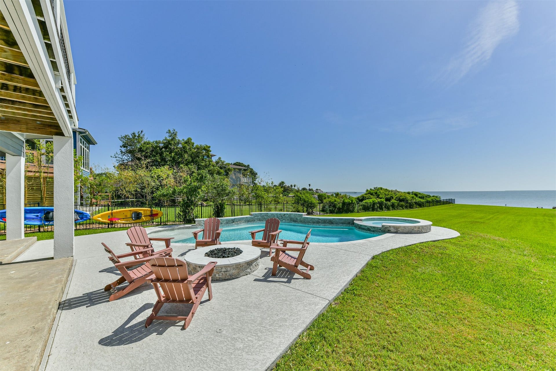 Experience serene waterfront living with a stunning outdoor retreat featuring a sparkling pool, cozy fire pit, and panoramic ocean views.