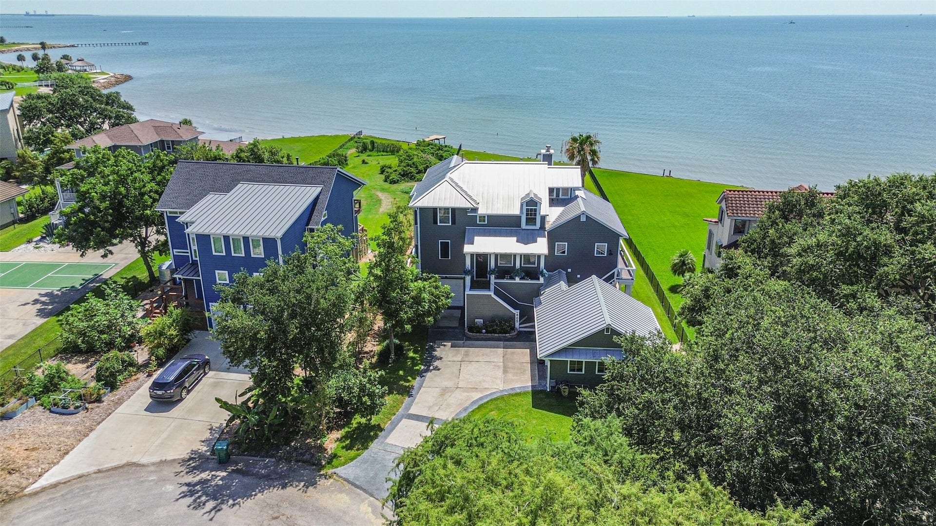 Stunning coastal home with direct ocean views, featuring a spacious layout, lush green lawn, and a private driveway. Perfect for enjoying serene seaside living.