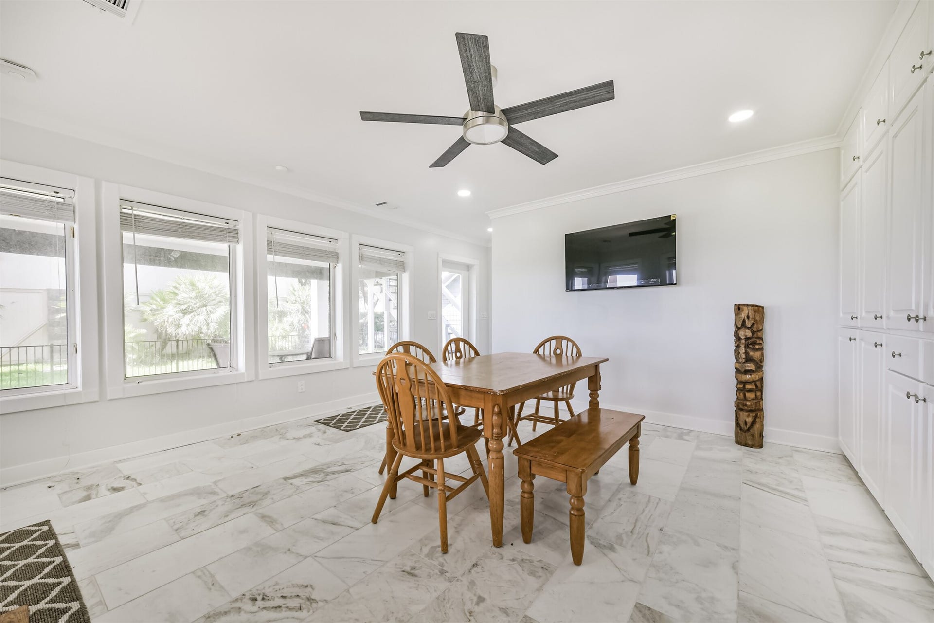 Dining area featuring large windows, elegant marble flooring, a modern ceiling fan, and ample built-in storage.